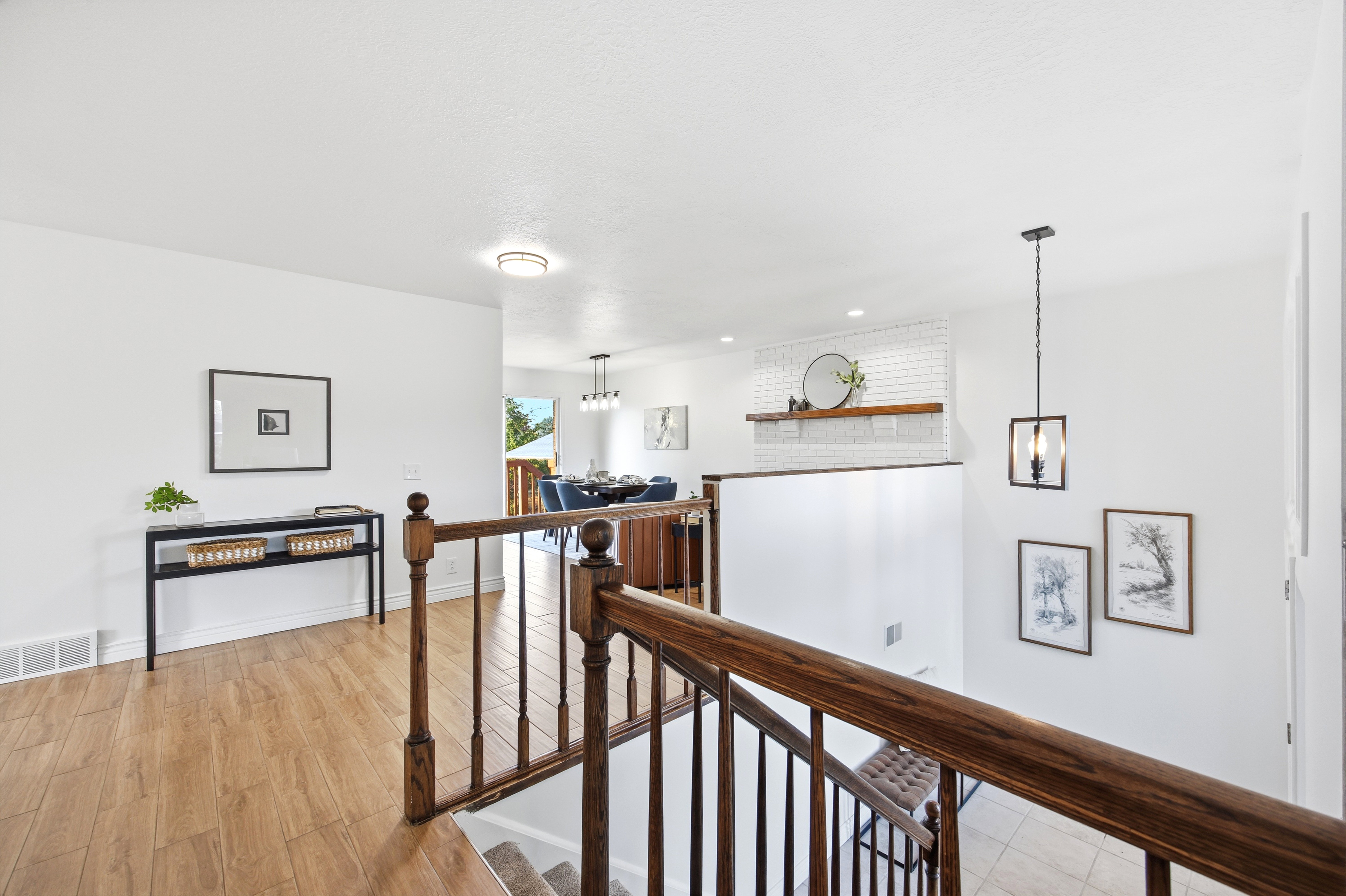 Upper-level landing featuring wood-finish flooring, a wood banister, and a contemporary pendant light fixture