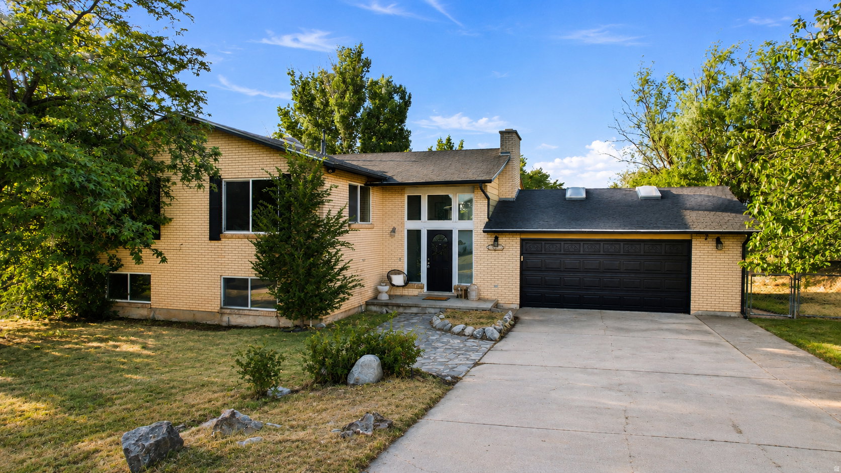 Brick exterior with an attached two-car garage, concrete driveway, and stone pathway