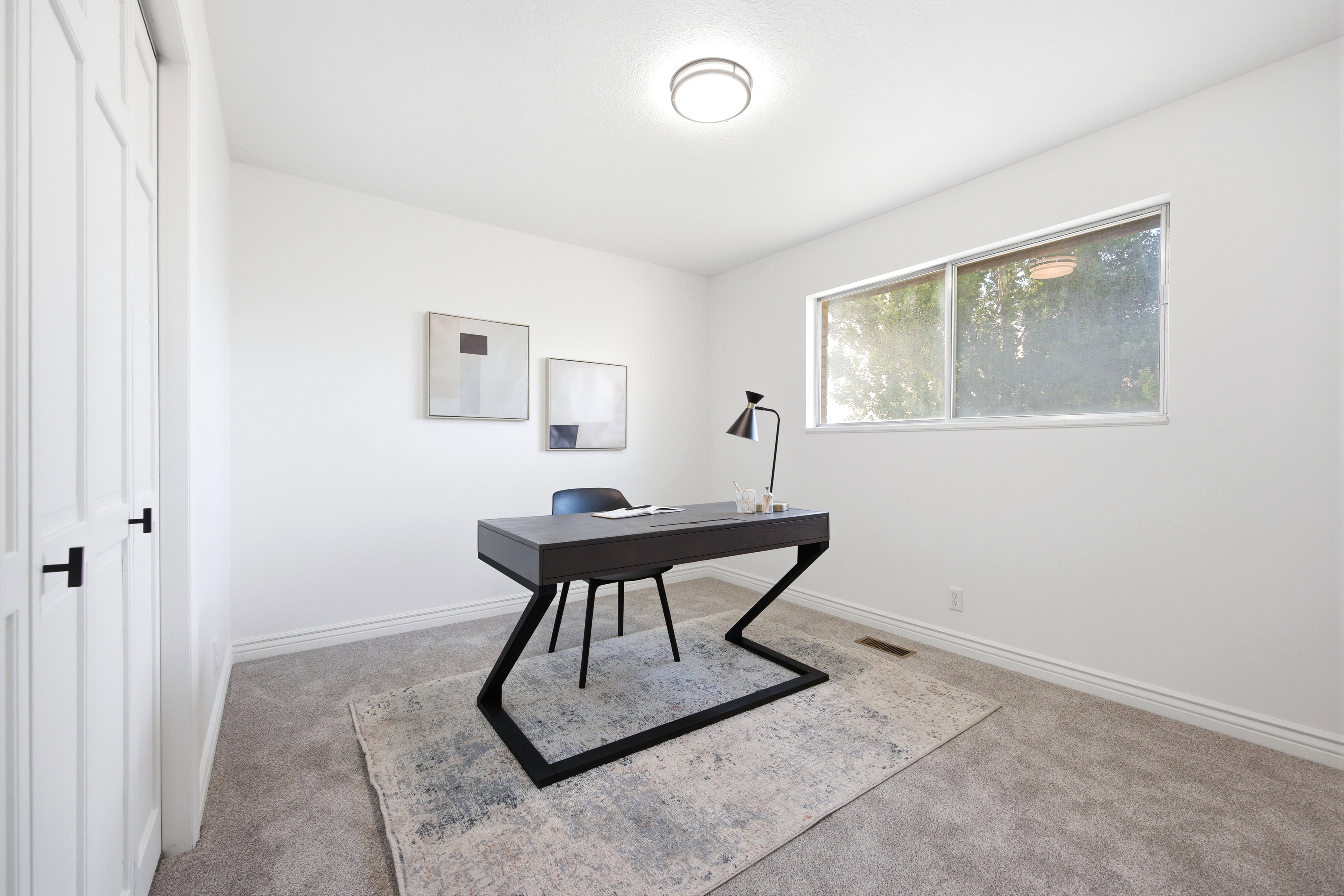 Bright room featuring a large window, plush gray carpeting, white baseboards, and a contemporary ceiling light fixture