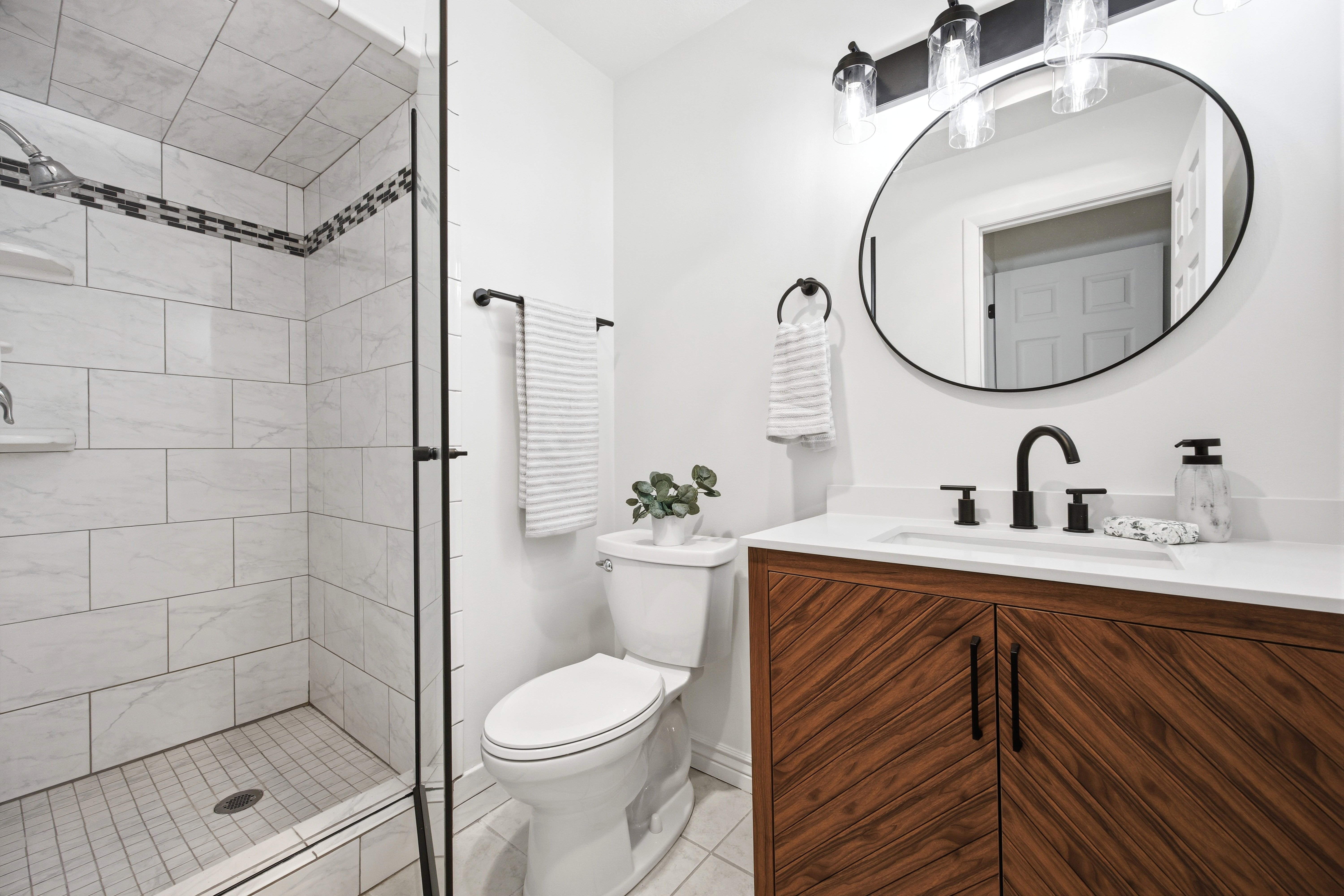 Contemporary bathroom featuring a patterned wood-finish vanity with a white countertop and undermount sink