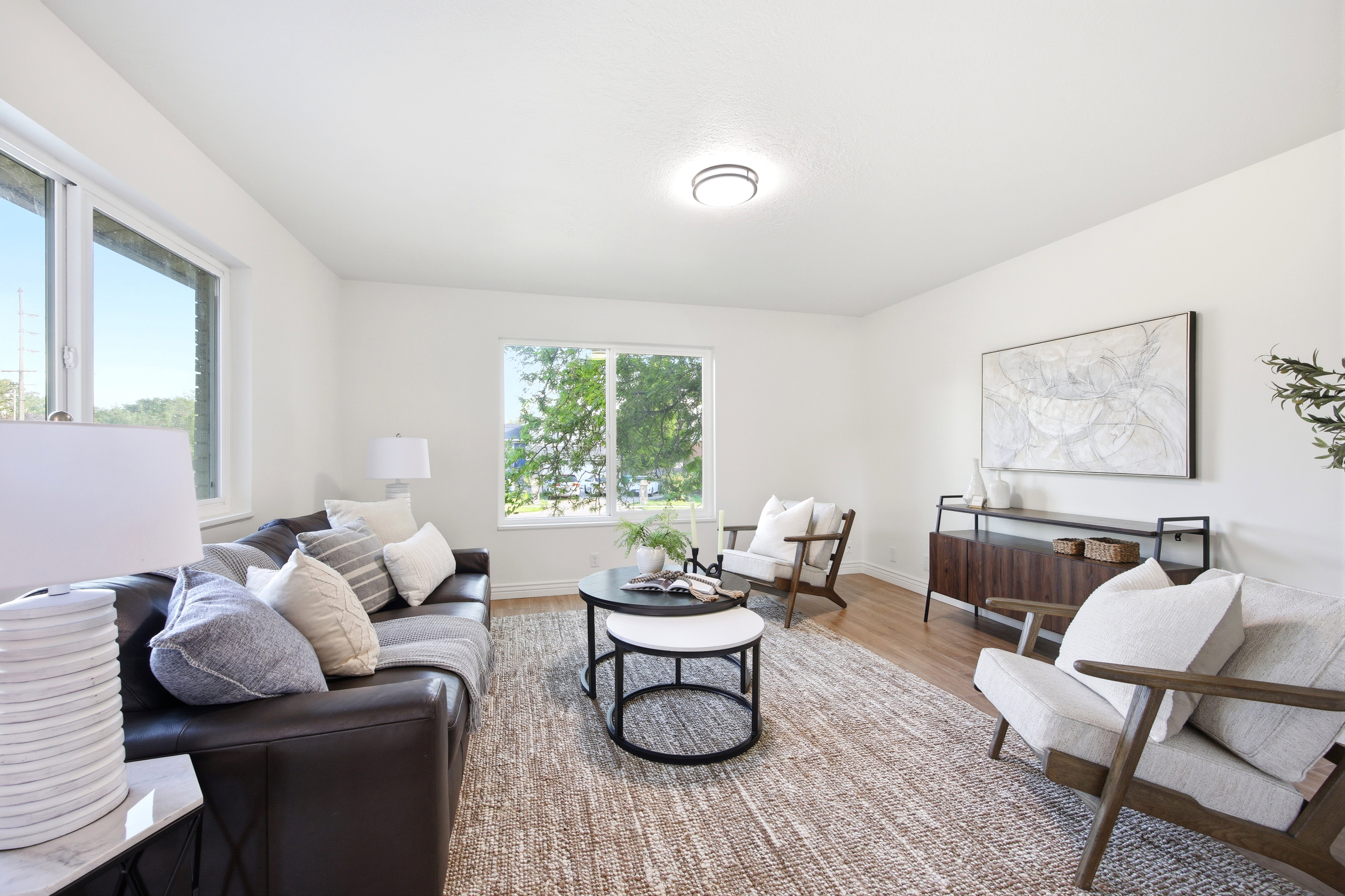Bright living area featuring wood-finish flooring, white walls, and multiple windows
