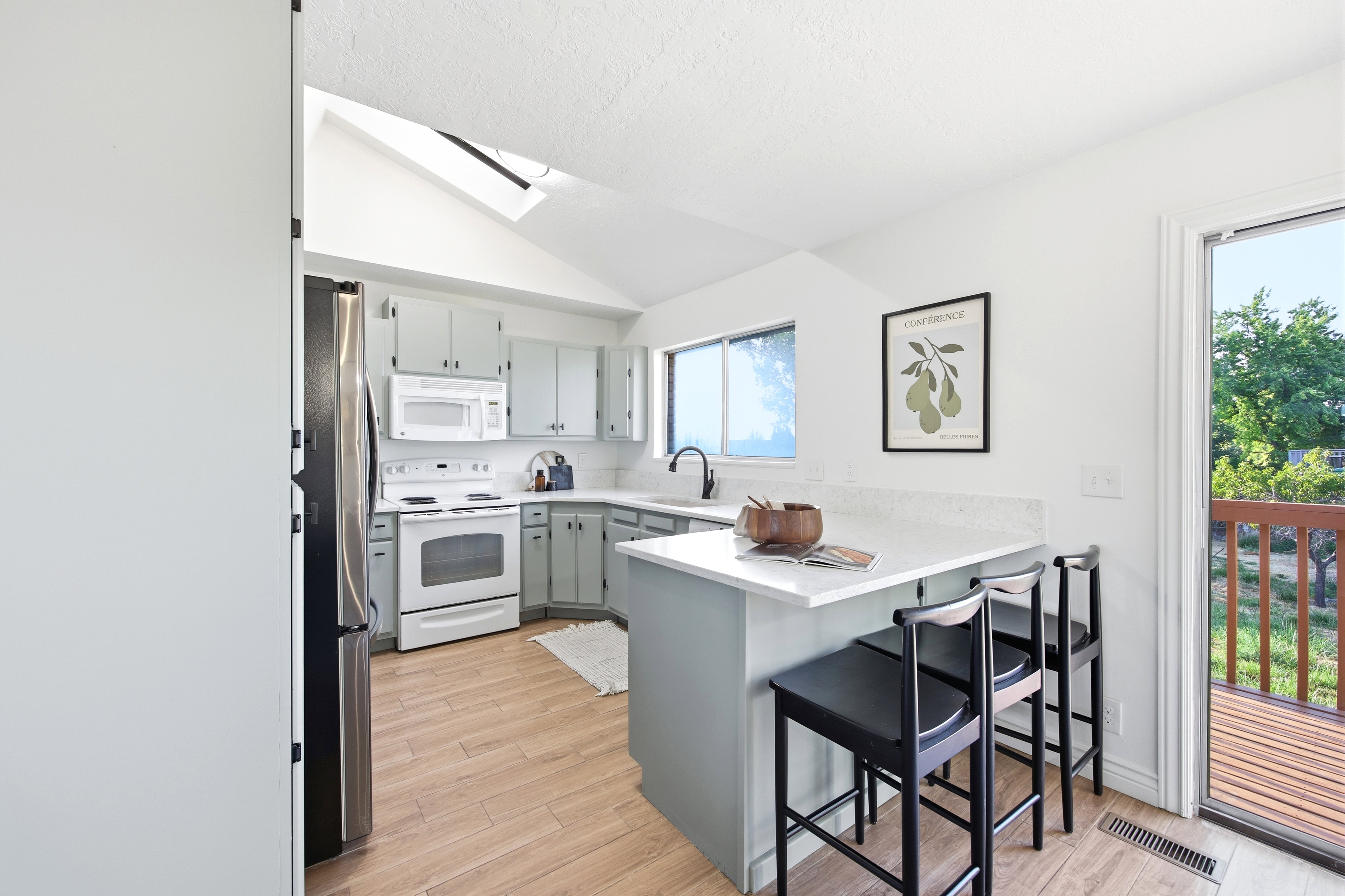 Kitchen featuring light gray cabinetry, white countertops, wood-finish flooring, a white range, and a stainless steel refrigerator