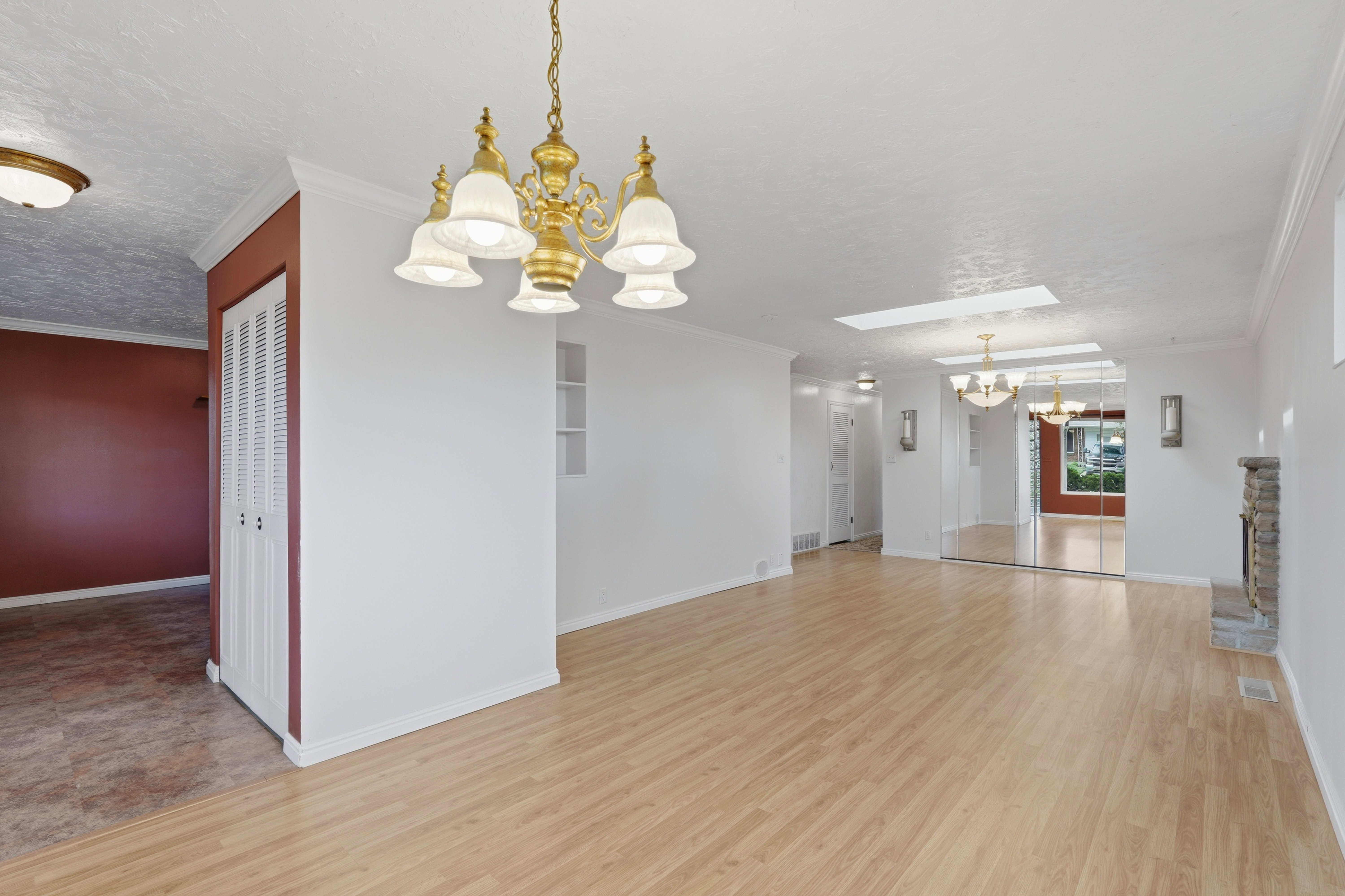 Spacious interior with wood-finish flooring, a brass chandelier, and a stone fireplace