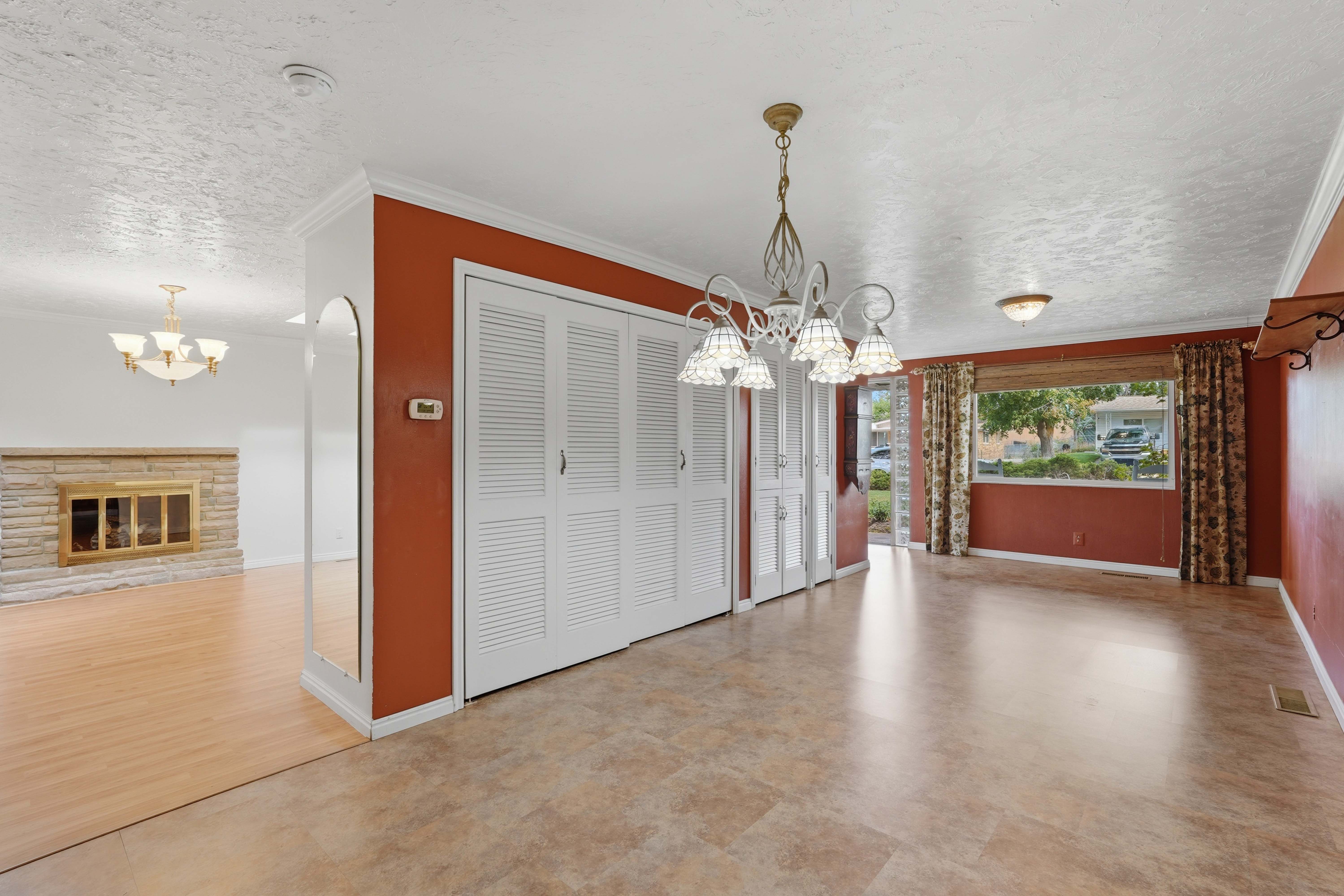 Spacious room featuring durable tile-look flooring, louvered bi-fold doors, and a decorative chandelier