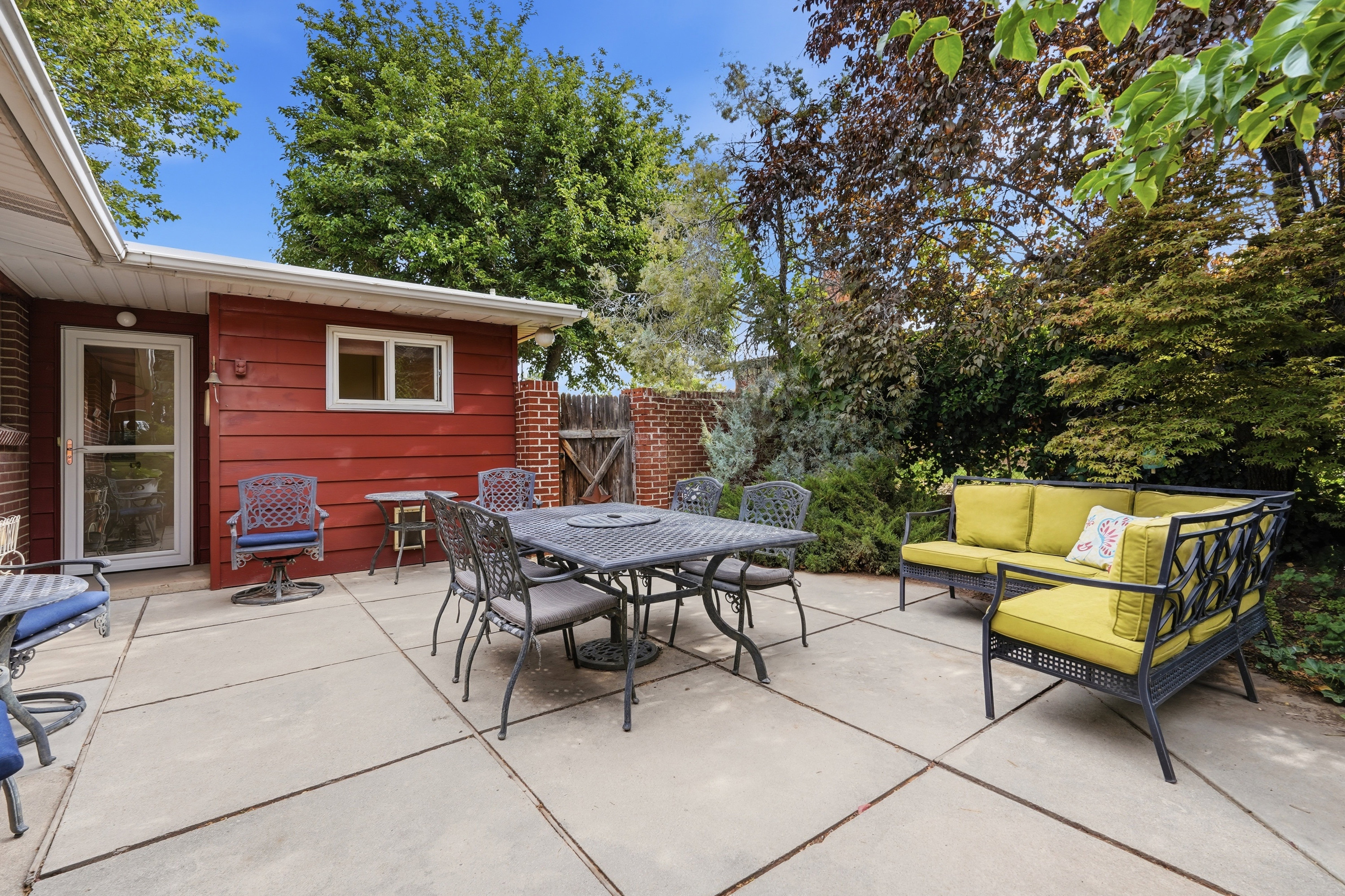 Expansive concrete patio area, featuring a red horizontal siding exterior wall with a white-framed window and a glass-paneled door