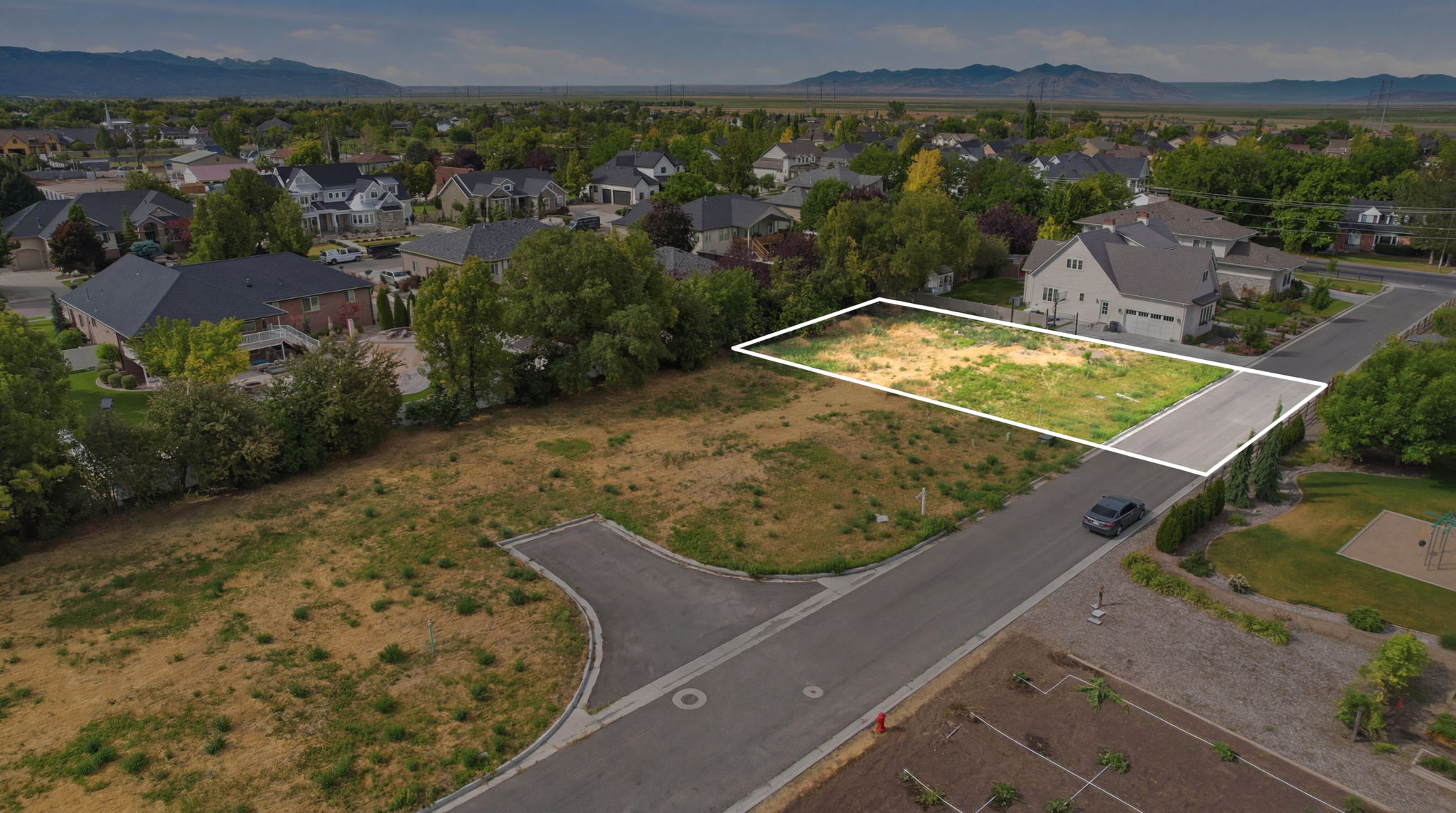 Flat, level building lot featuring street frontage, mature landscaping surrounding, and mountain backdrop