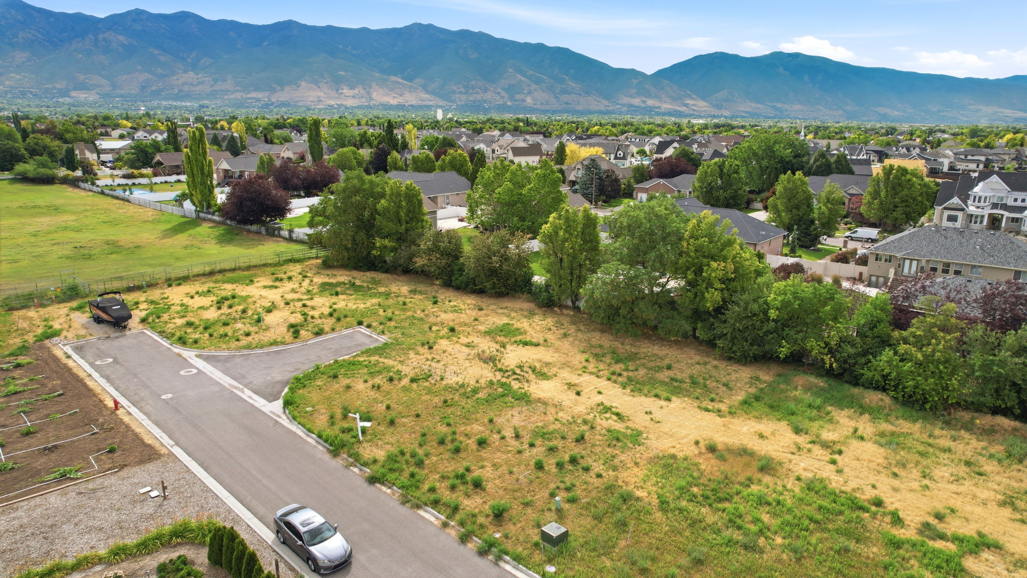 Expansive undeveloped land parcel featuring existing paved road frontage and utility access points