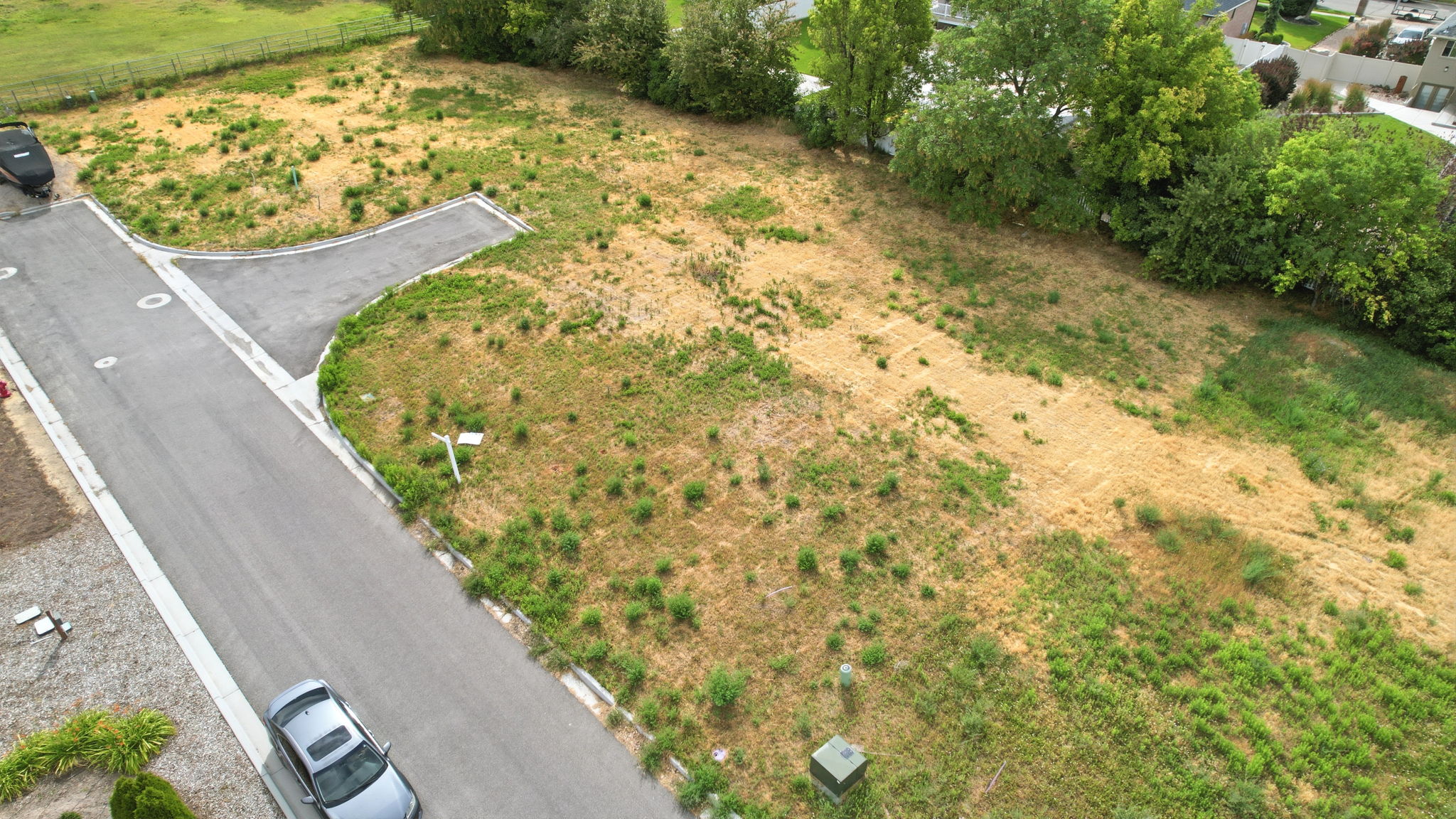 Expansive land parcel featuring established paved road access, designated utility connections, and mature perimeter trees
