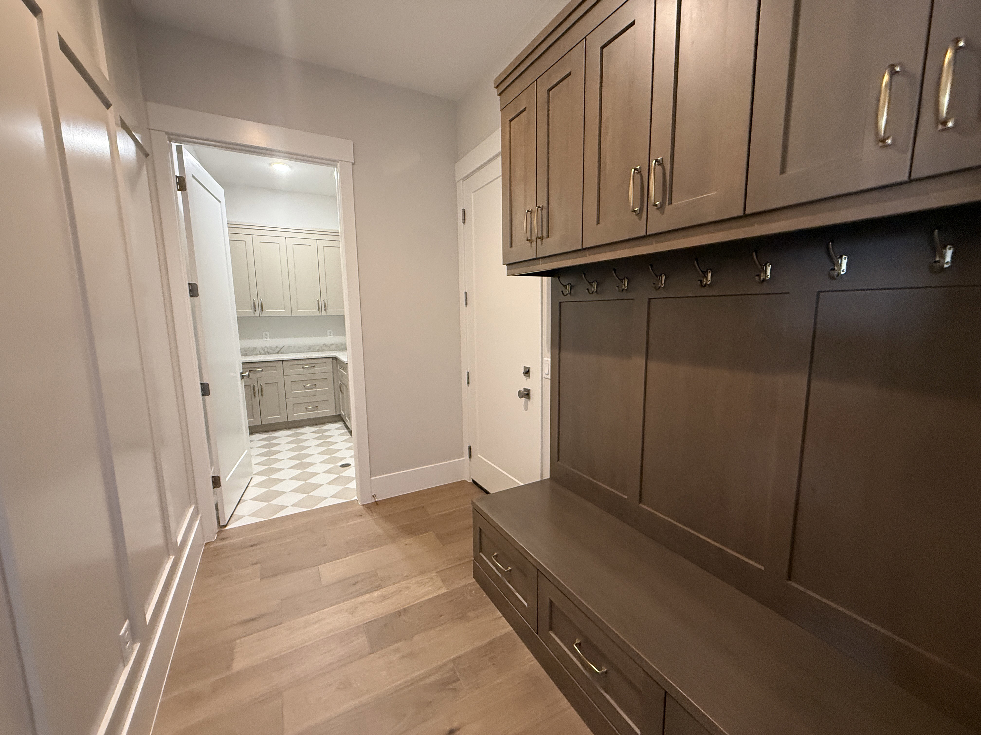 Entryway featuring wood-finish flooring, wainscoting, and a built-in mudroom bench with storage drawers and upper cabinetry