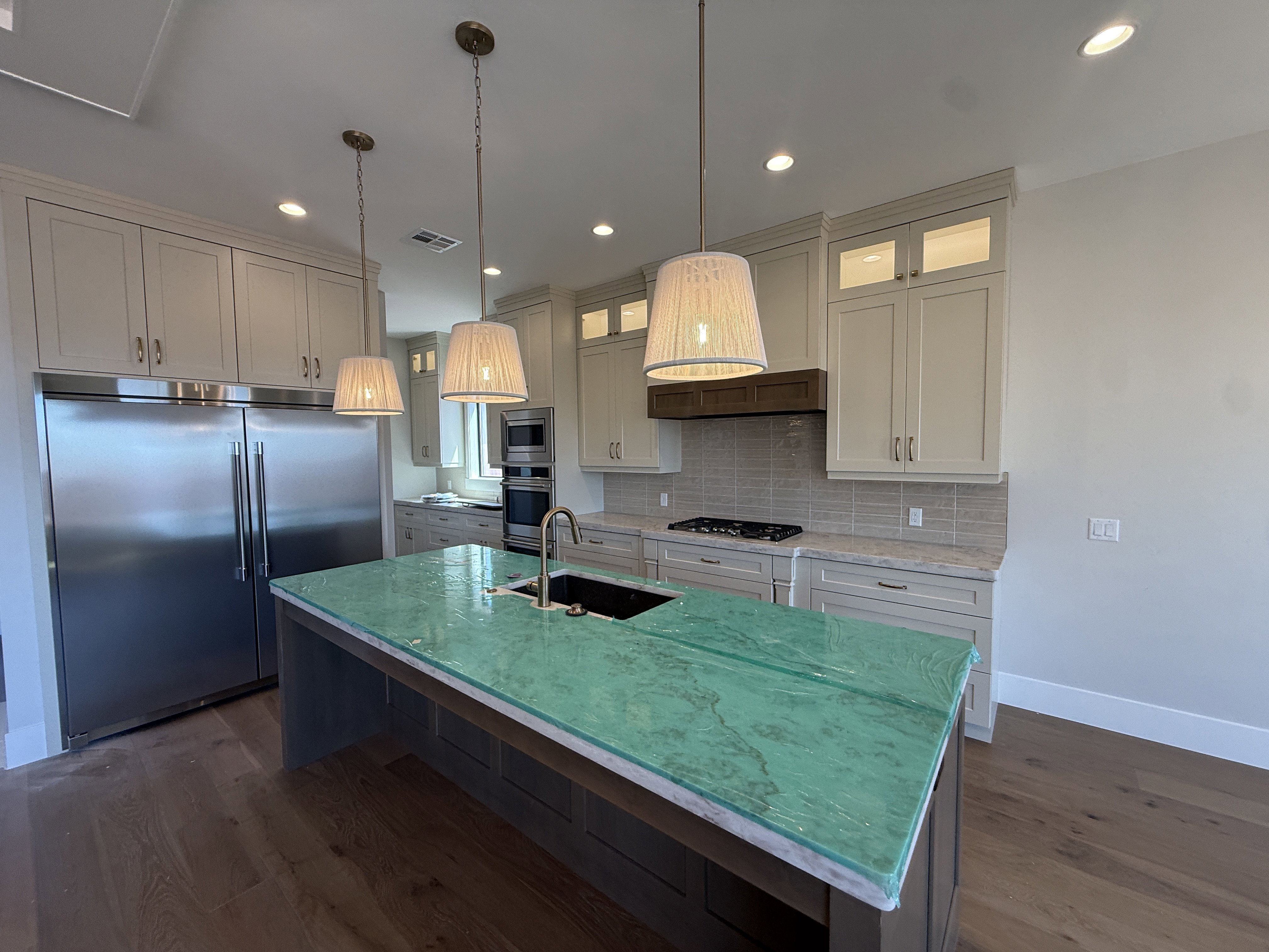 Kitchen island featuring a green stone countertop with an undermount sink