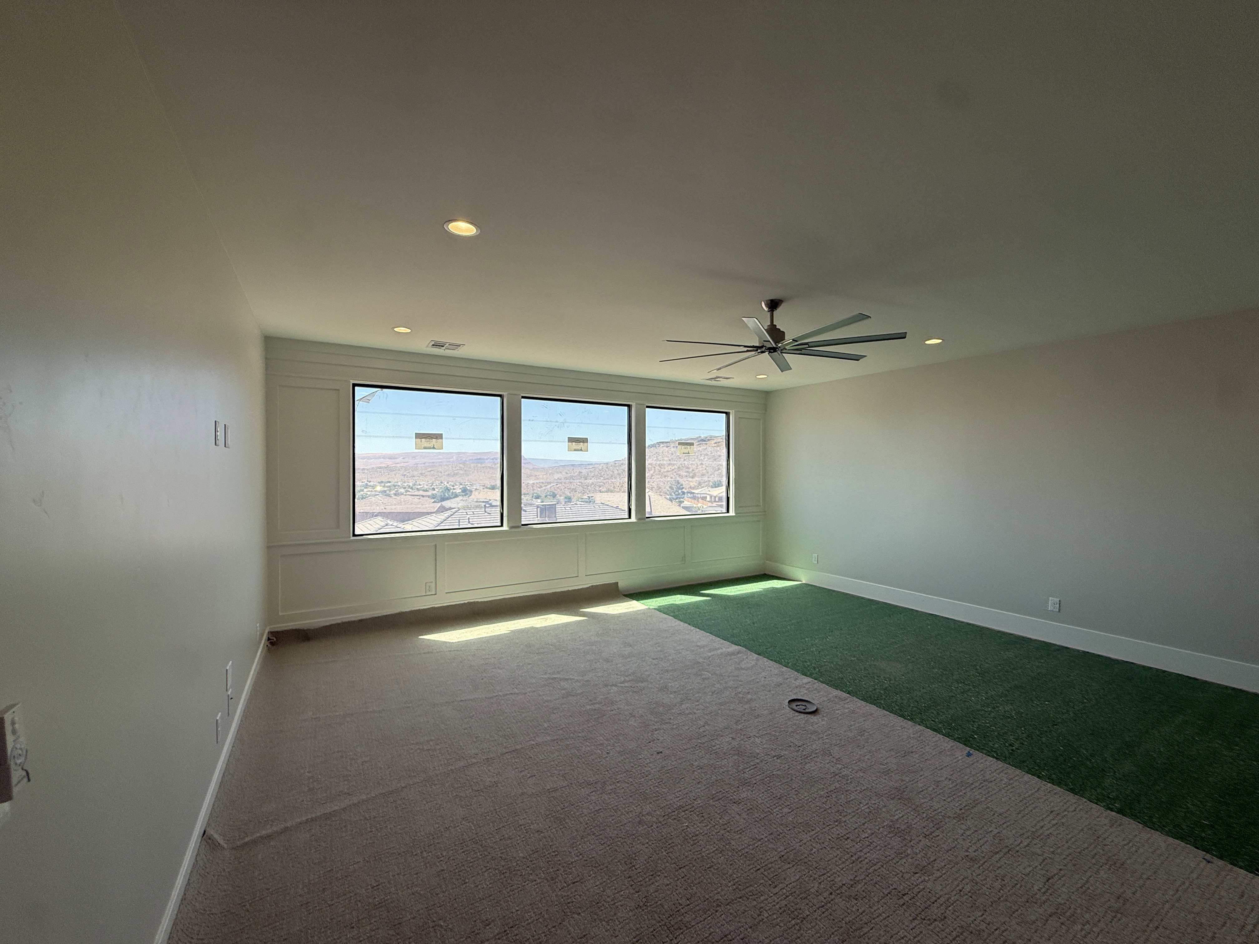 Expansive room featuring a multi-paned window wall, recessed lighting, and a ceiling fan