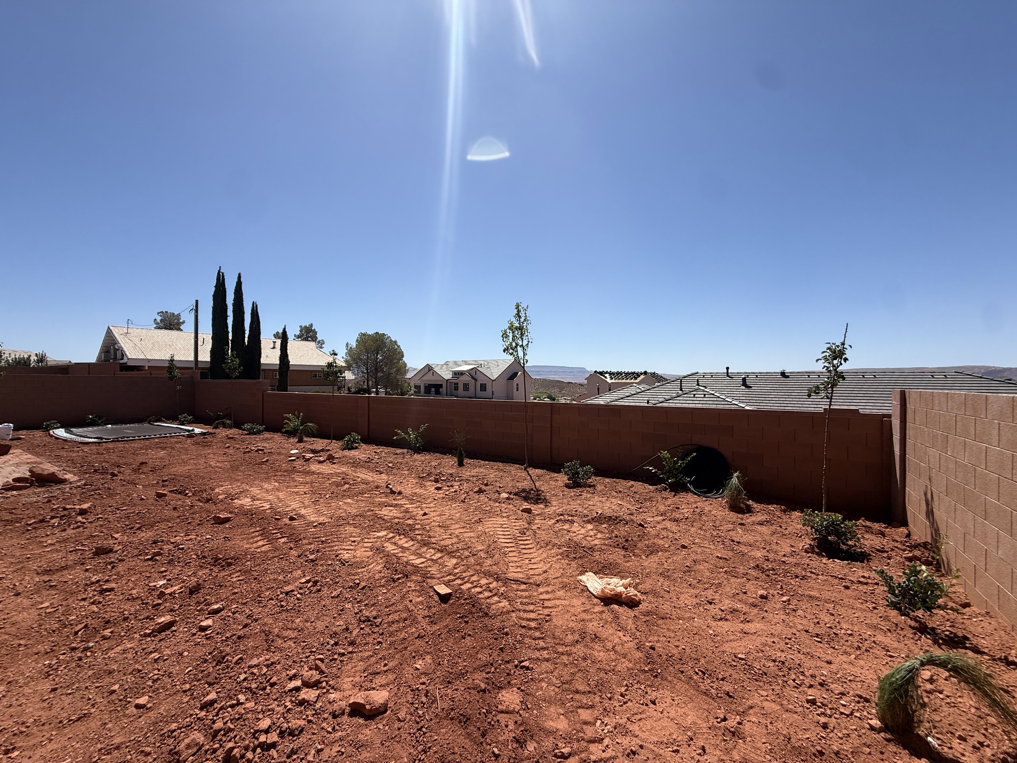 Expansive backyard featuring a red earth landscape and a solid block wall perimeter
