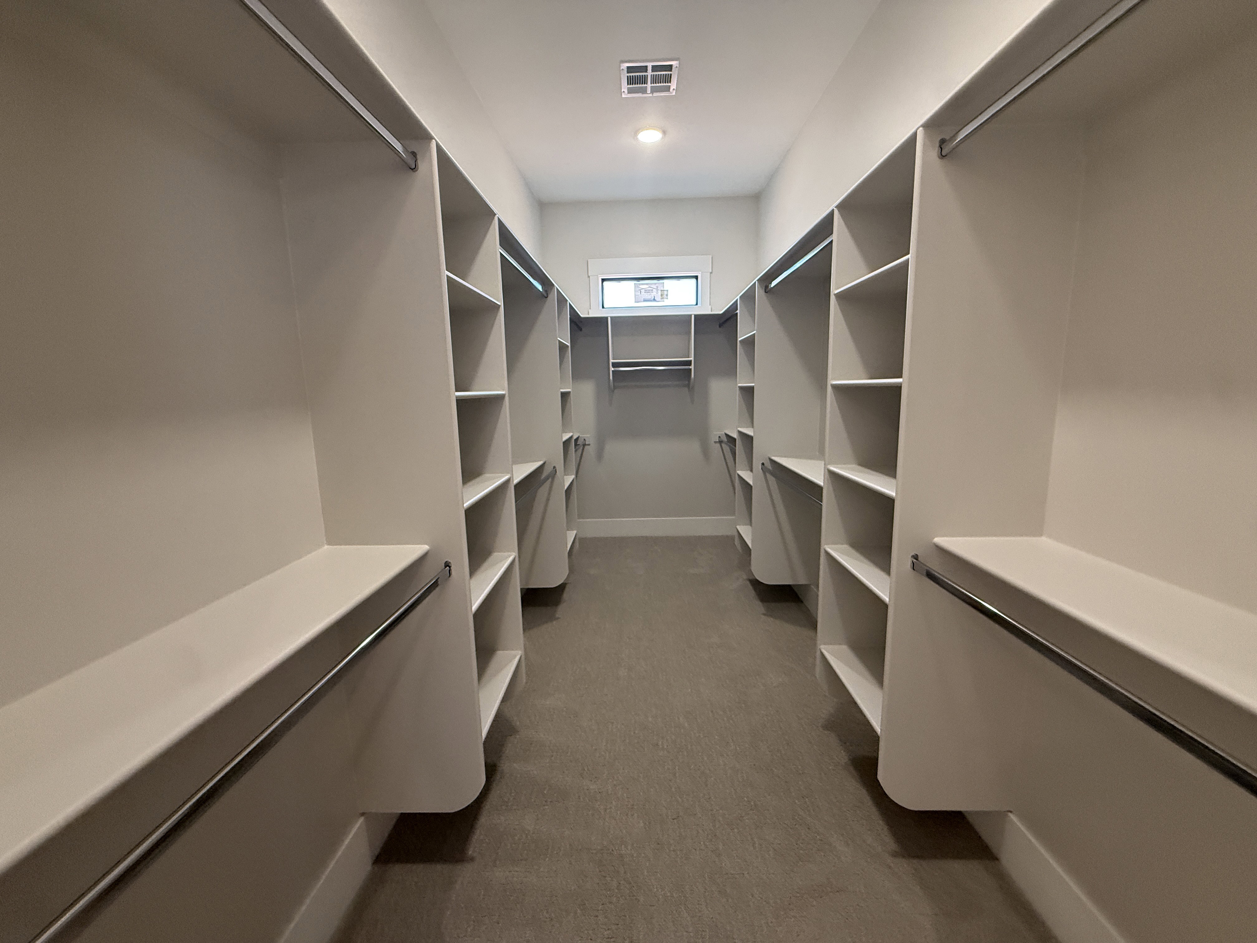Walk-in closet featuring extensive built-in shelving, multiple hanging rods, recessed lighting, and a window for natural light