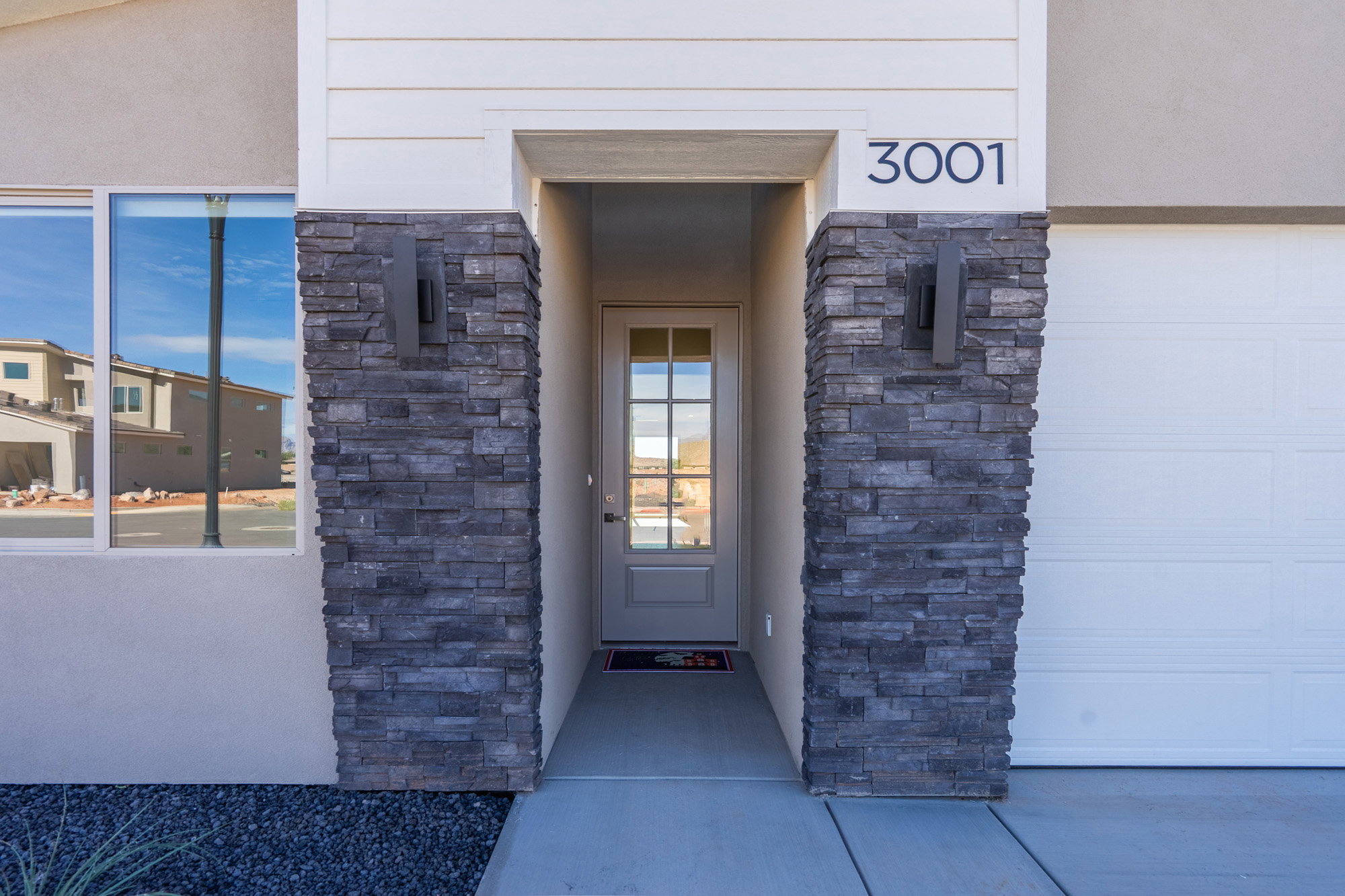Doorway to property with stone siding, stucco siding, and a garage