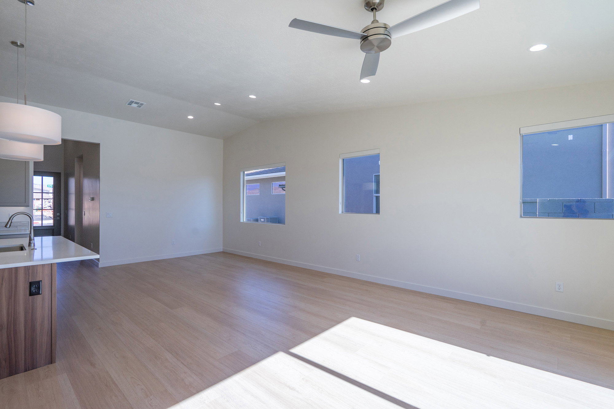 Spare room featuring light wood-type flooring, lofted ceiling, recessed lighting, a ceiling fan, and plenty of natural light