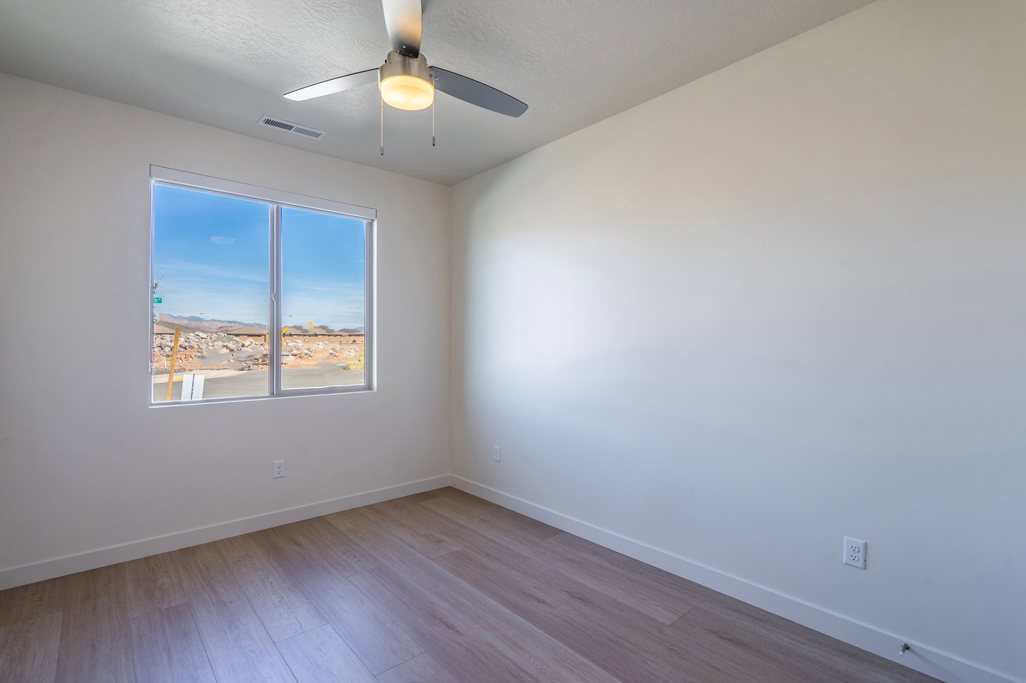 Empty room with ceiling fan and light wood finished floors