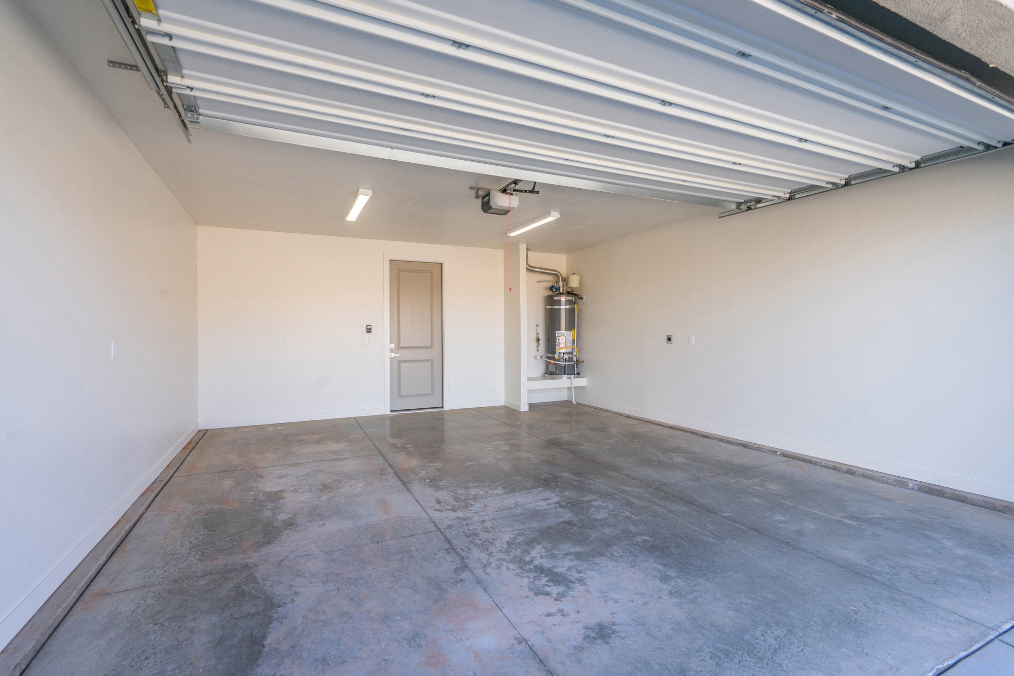 Garage with strapped water heater and baseboards