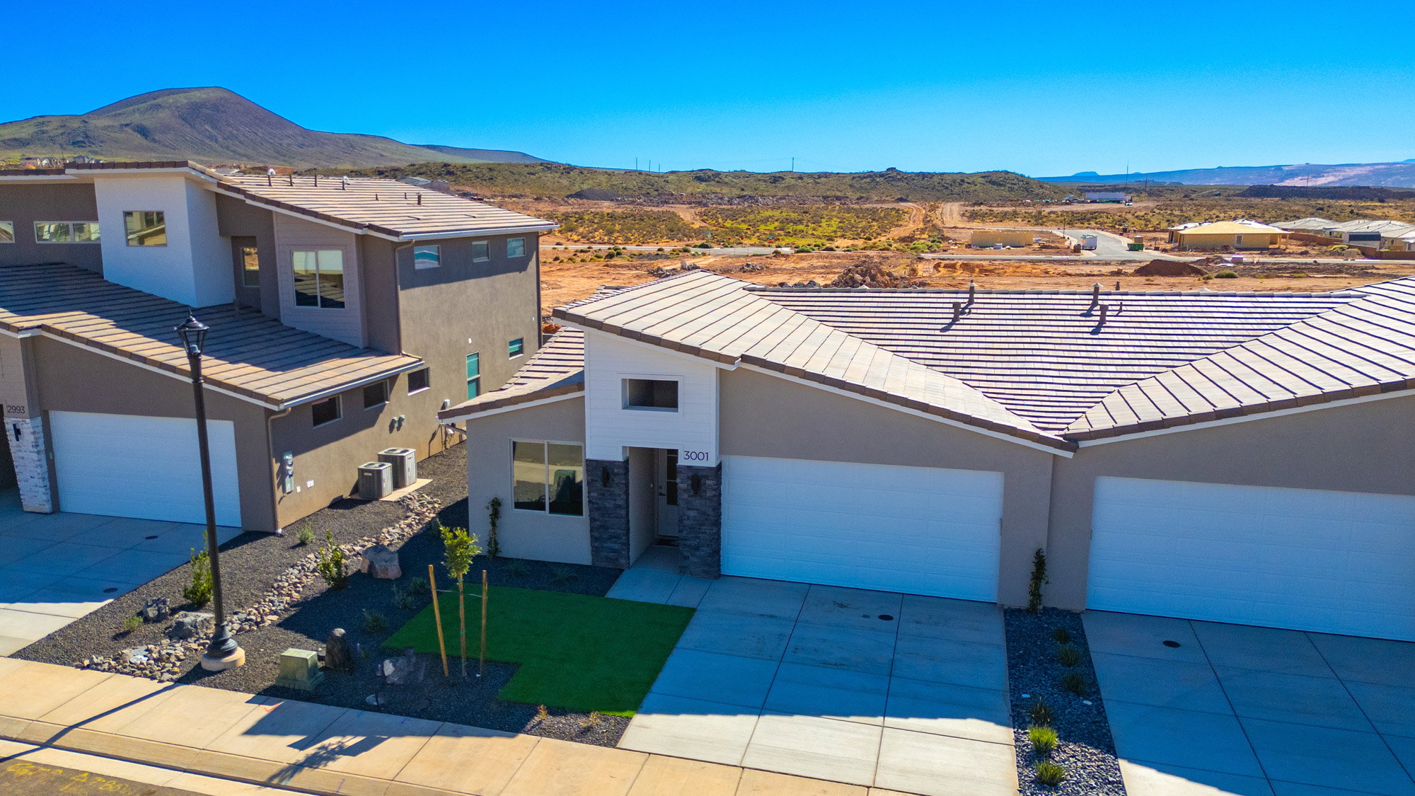 View of front facade with a mountain view, stucco siding, concrete driveway, a tile roof, and stone siding
