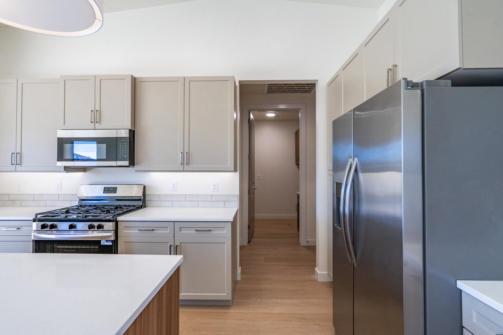 Kitchen featuring stainless steel appliances, gray cabinets, light wood-type flooring, and light stone countertops