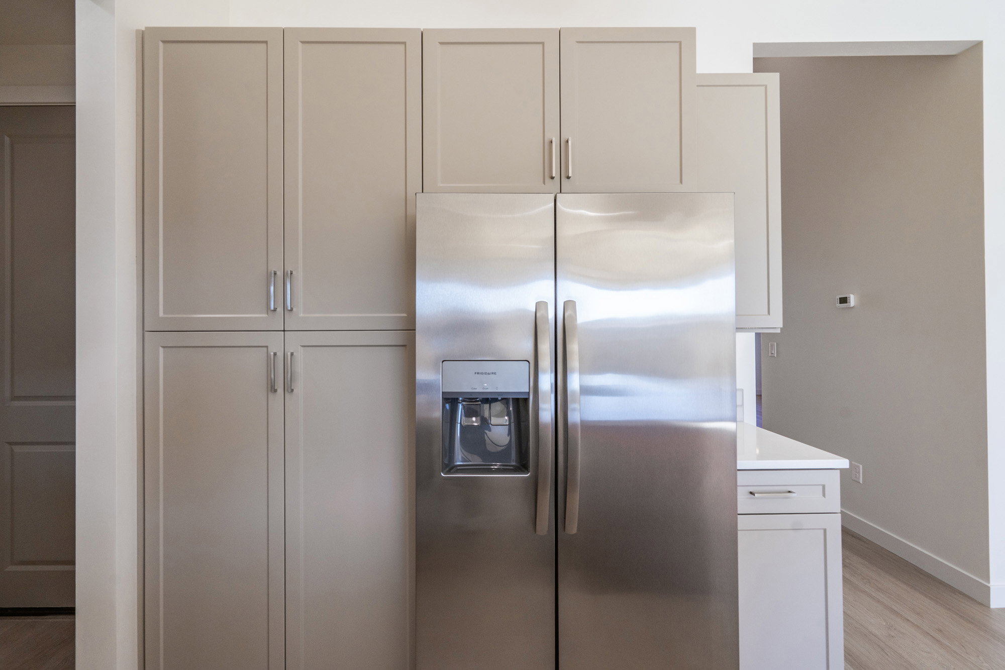 Kitchen featuring stainless steel fridge, light wood-style floors, and light stone counters