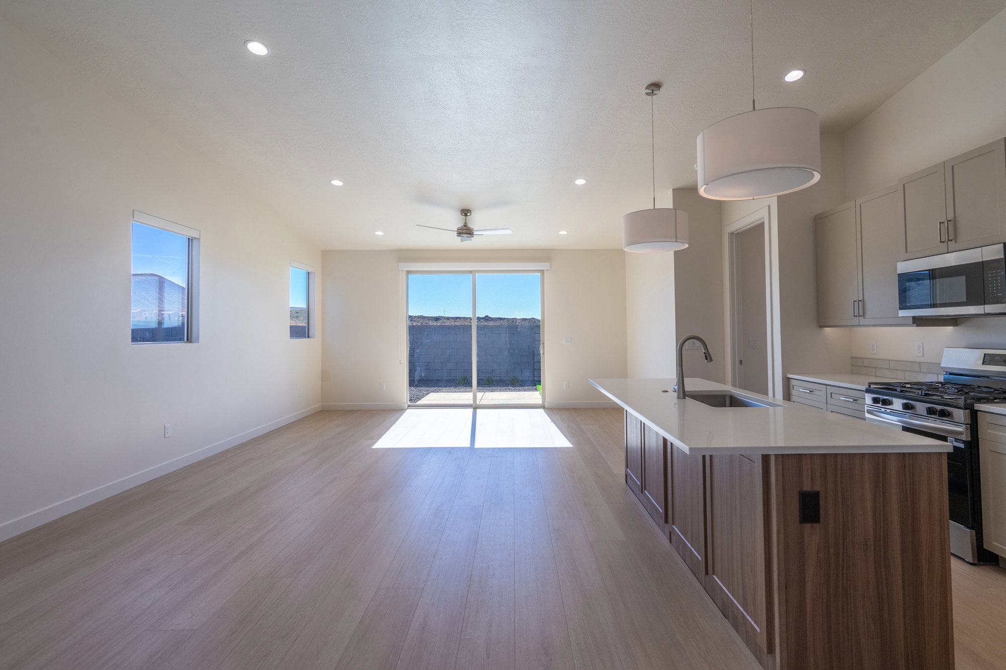 Kitchen featuring stainless steel appliances, open floor plan, light wood-type flooring, hanging light fixtures, and ceiling fan