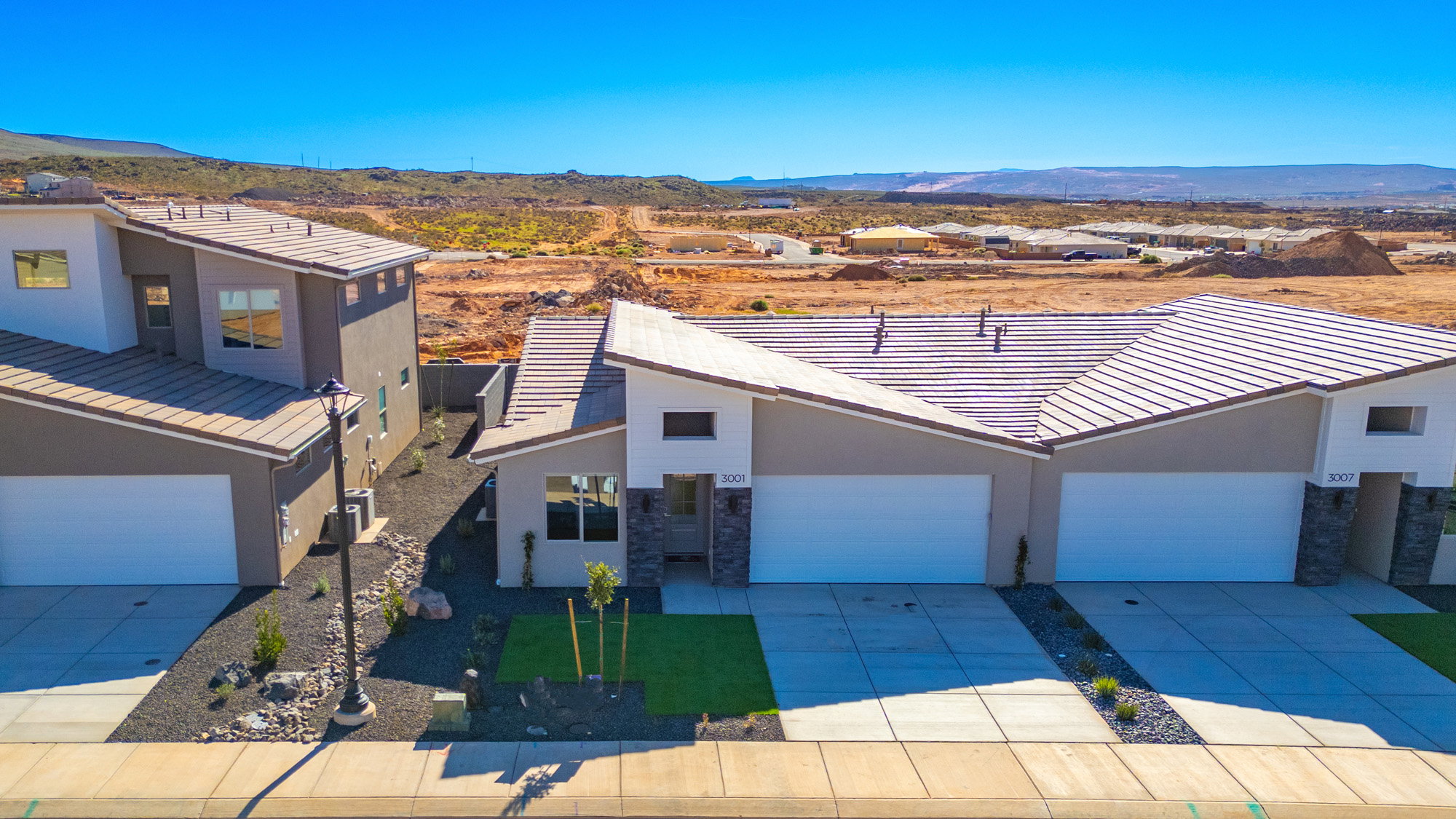 View of front of property with concrete driveway, an attached garage, a mountain view, and stucco siding