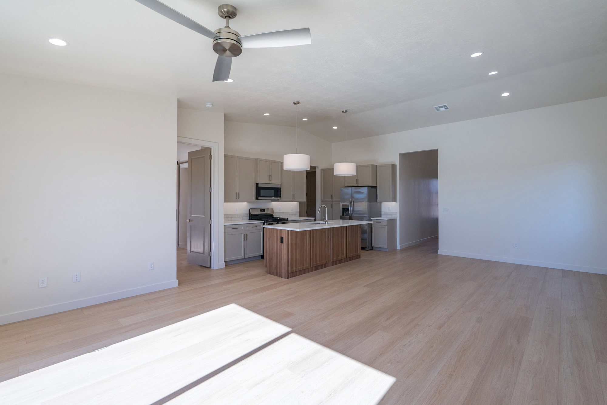 Kitchen with open floor plan, light wood finished floors, a center island with sink, hanging light fixtures, and vaulted ceiling
