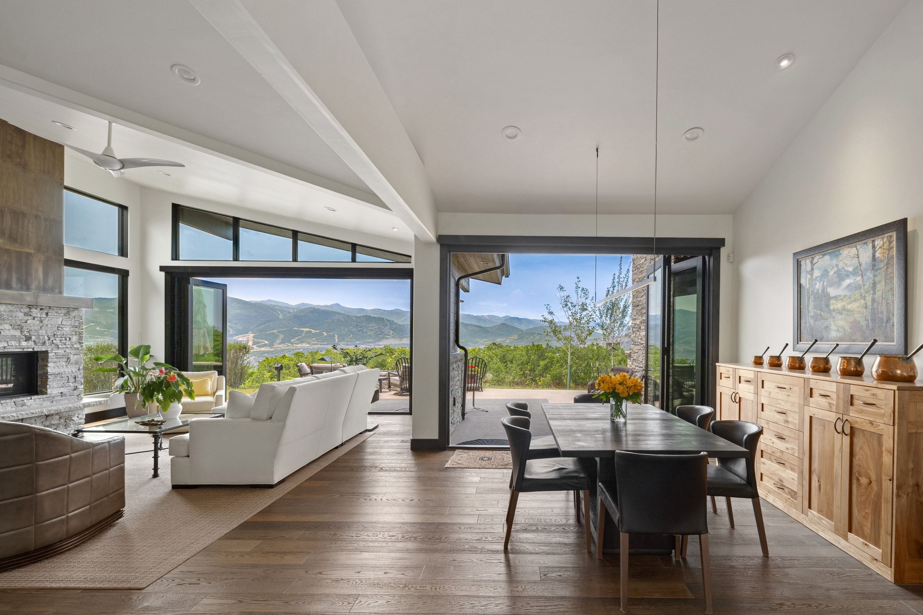 Expansive open-concept interior featuring wood-finish flooring, a stone-clad fireplace, and vaulted ceilings