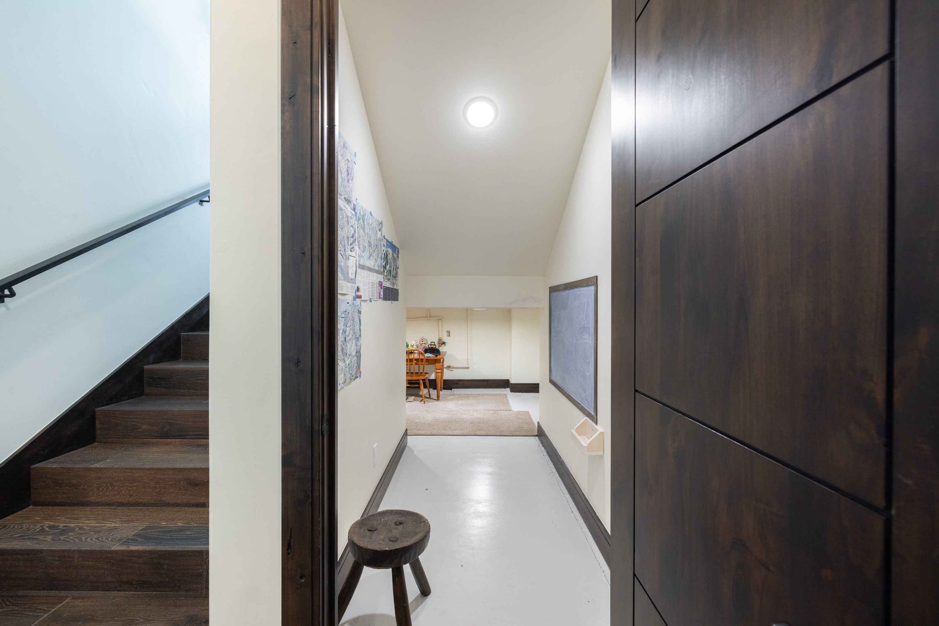 Hallway with white flooring, contemporary dark wood-finish door, and recessed ceiling lighting