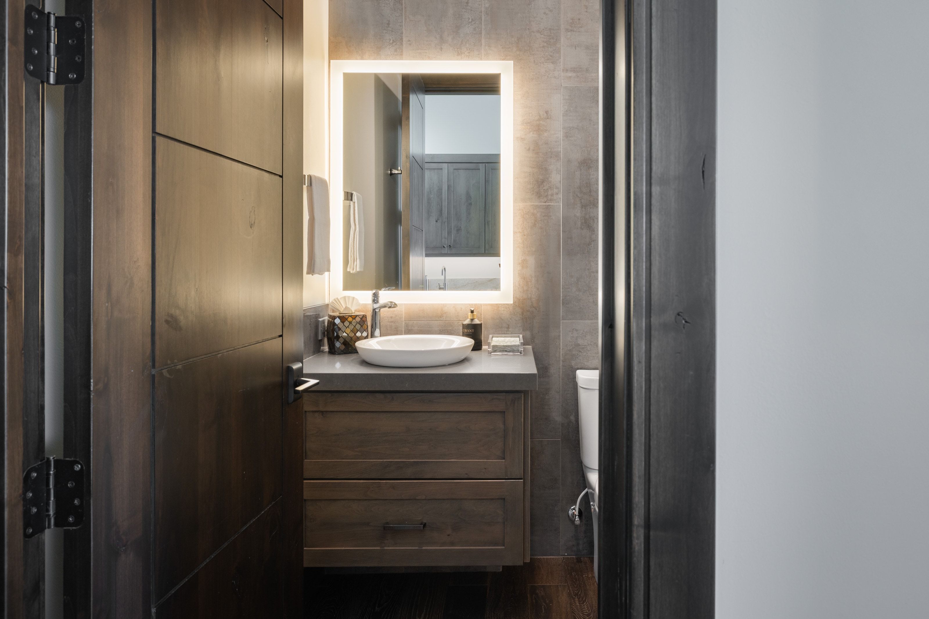 Modern vanity featuring a vessel sink, integrated LED mirror, and built-in storage