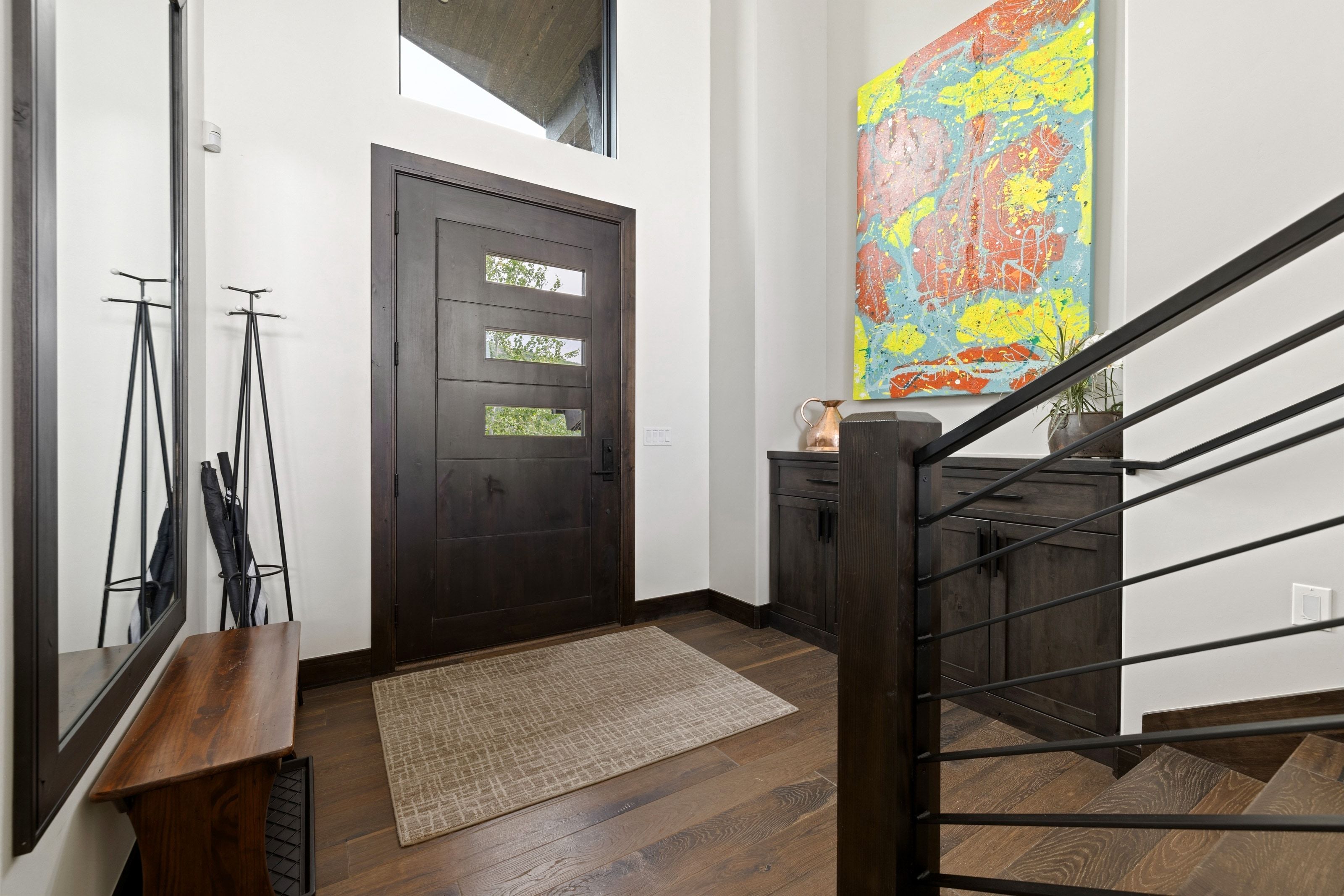 Modern entryway featuring a dark wood-finish door with three horizontal lites, a transom window, and rich wood-finish flooring