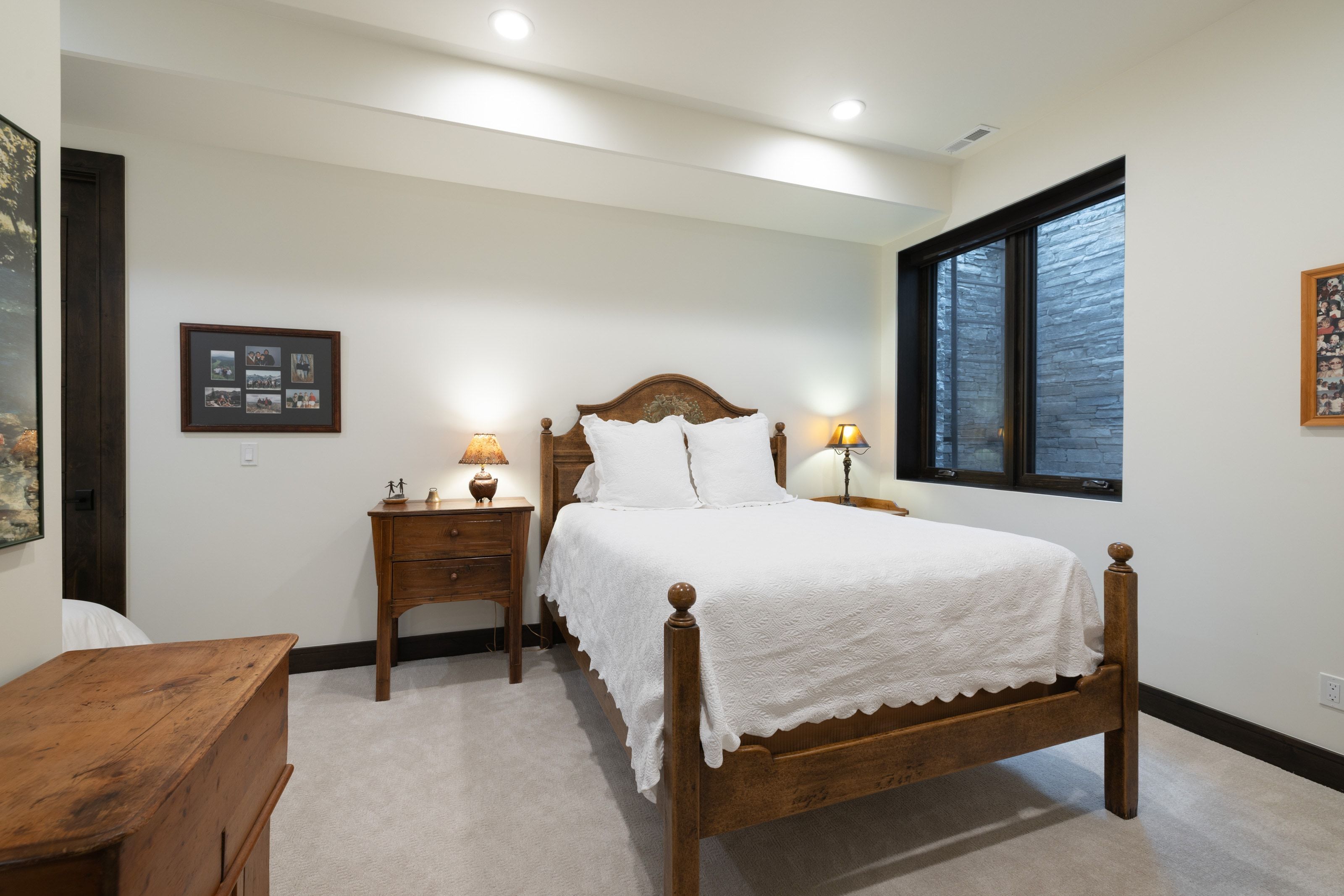 Carpeted bedroom featuring a dark wood door, recessed lighting, and a window with a stone-textured exterior