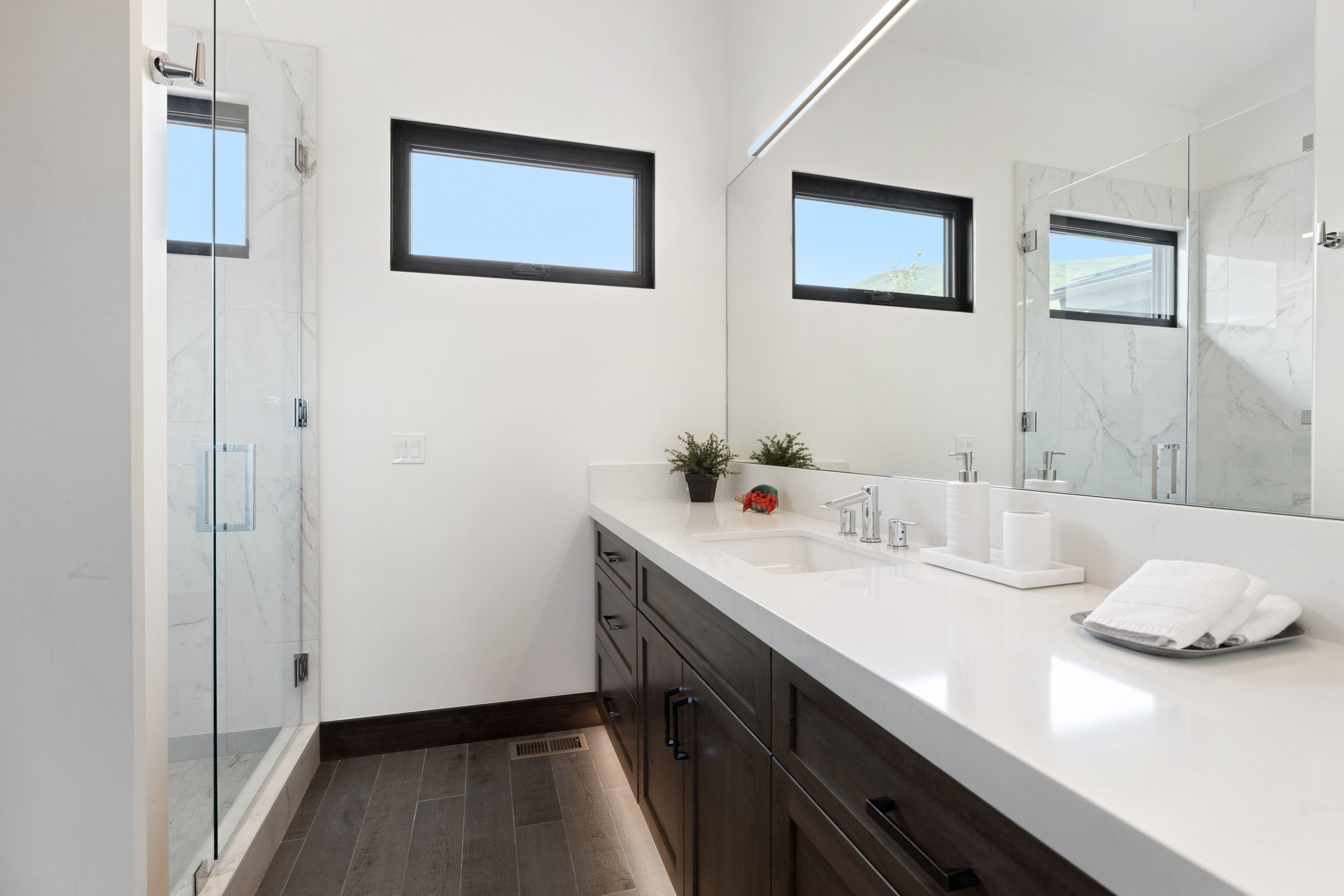 Contemporary bathroom featuring a dark wood-finish vanity with a white countertop and integrated sink