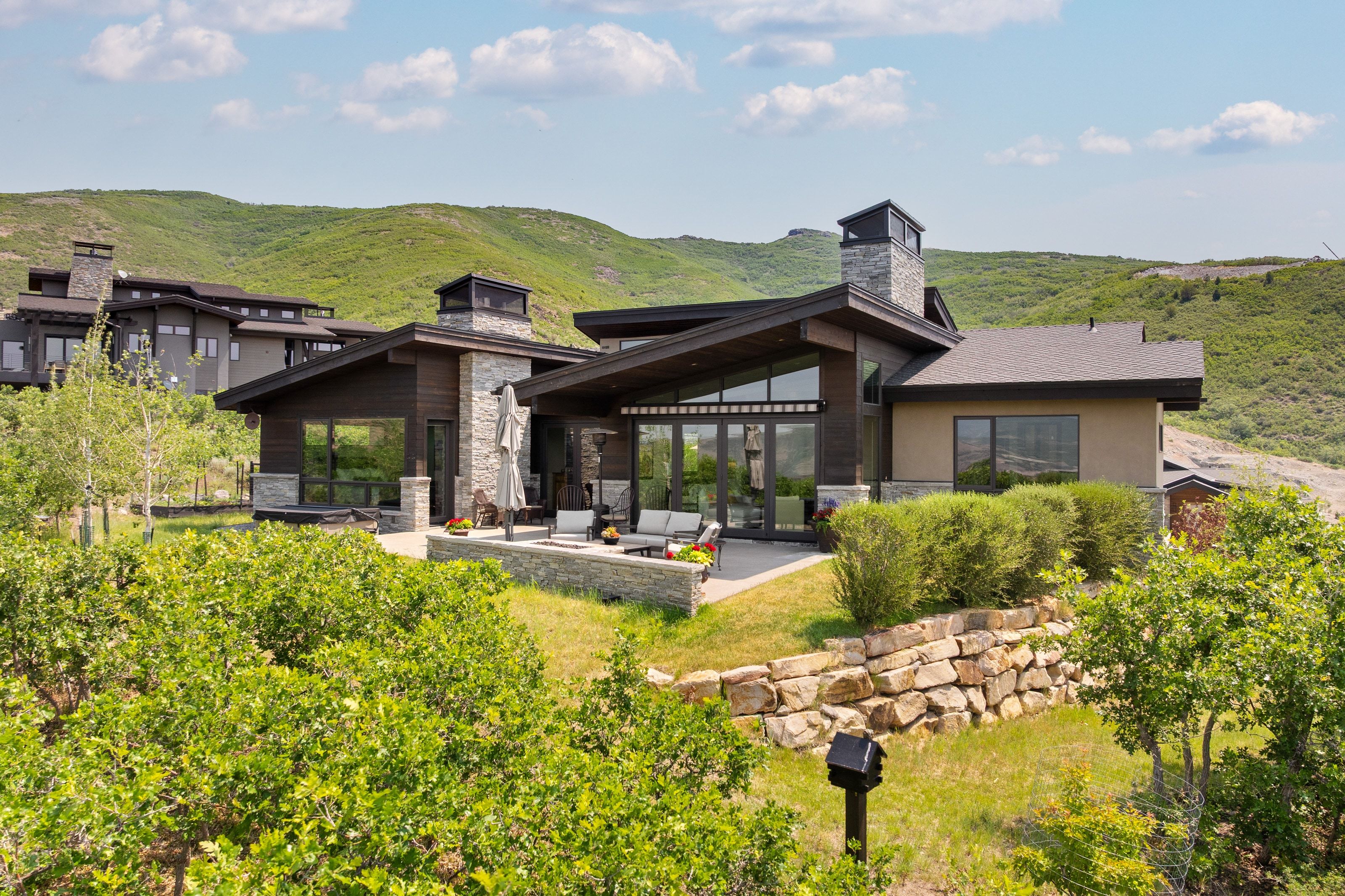 Contemporary exterior with stone and wood-finish siding, featuring a spacious patio area
