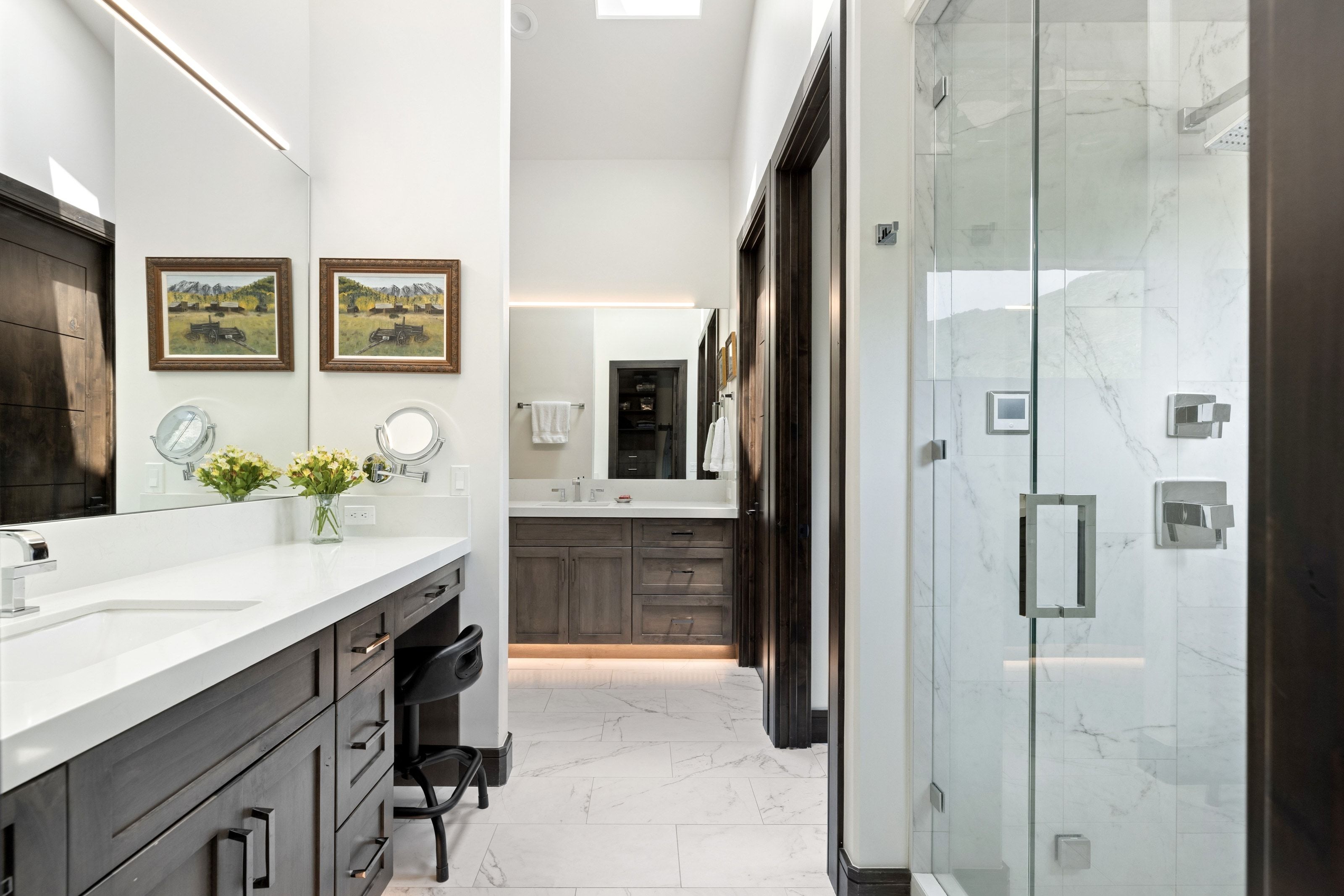 Spacious bathroom featuring a glass-enclosed shower with tile surround, double vanity with integrated sinks, wood-finish cabinetry, and recessed lighting