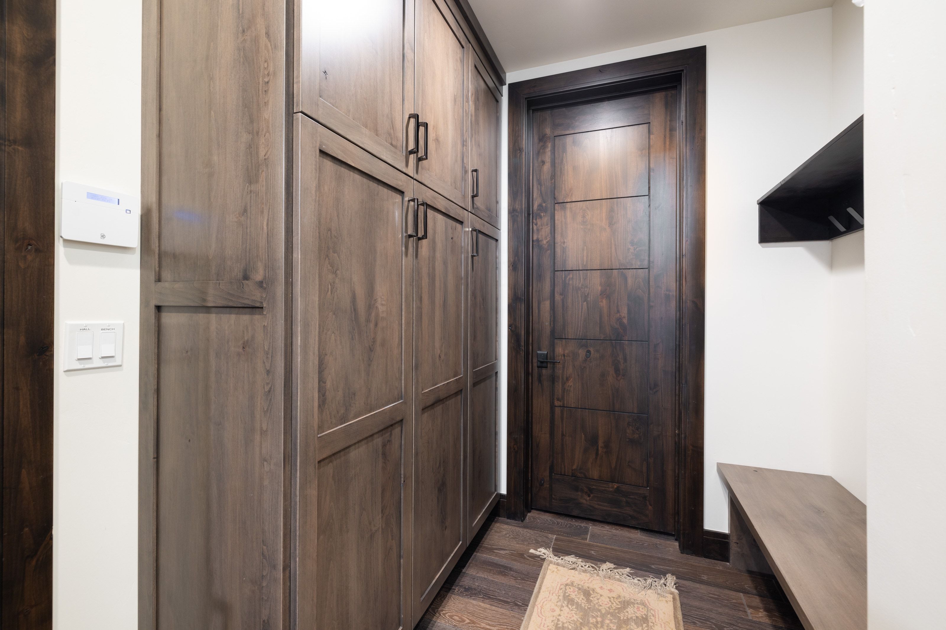 Extensive wood-finish built-in cabinetry with black hardware, complementing a dark wood-finish door with modern paneling