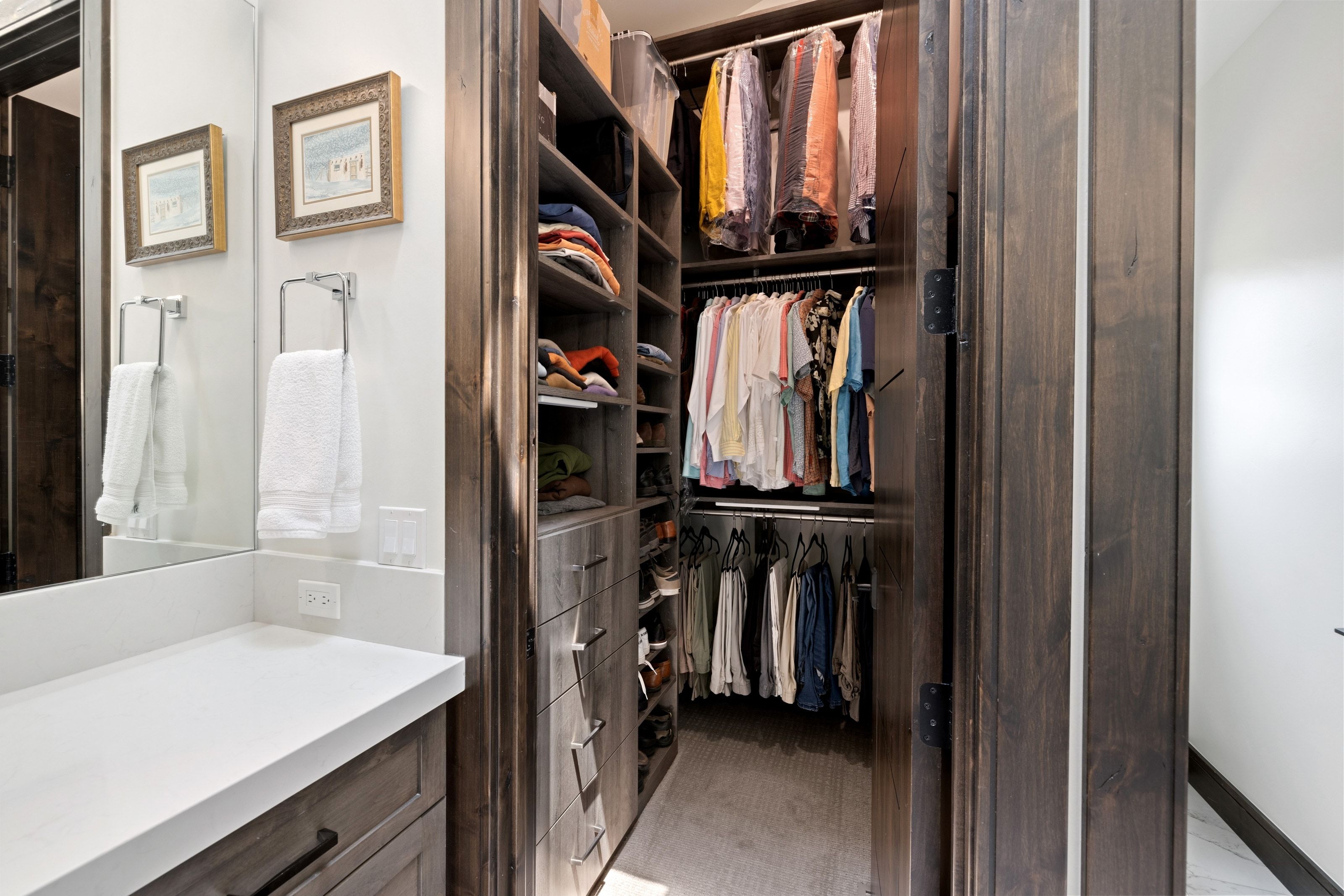 Custom closet system featuring dark wood-finish cabinetry, integrated shelving, and multiple hanging rods