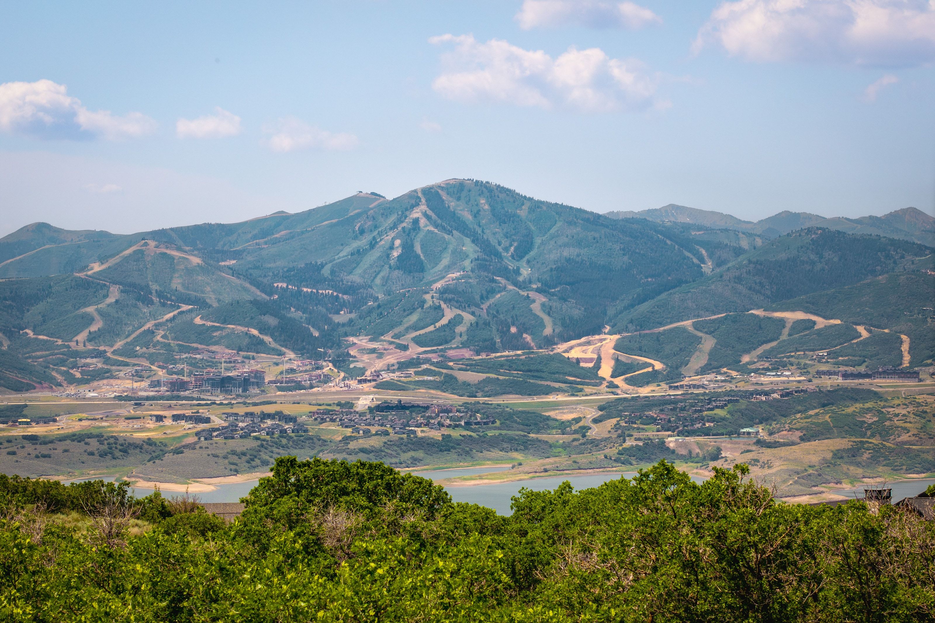 Expansive mountain scenery featuring distant ski slopes, a large body of water, and surrounding terrain