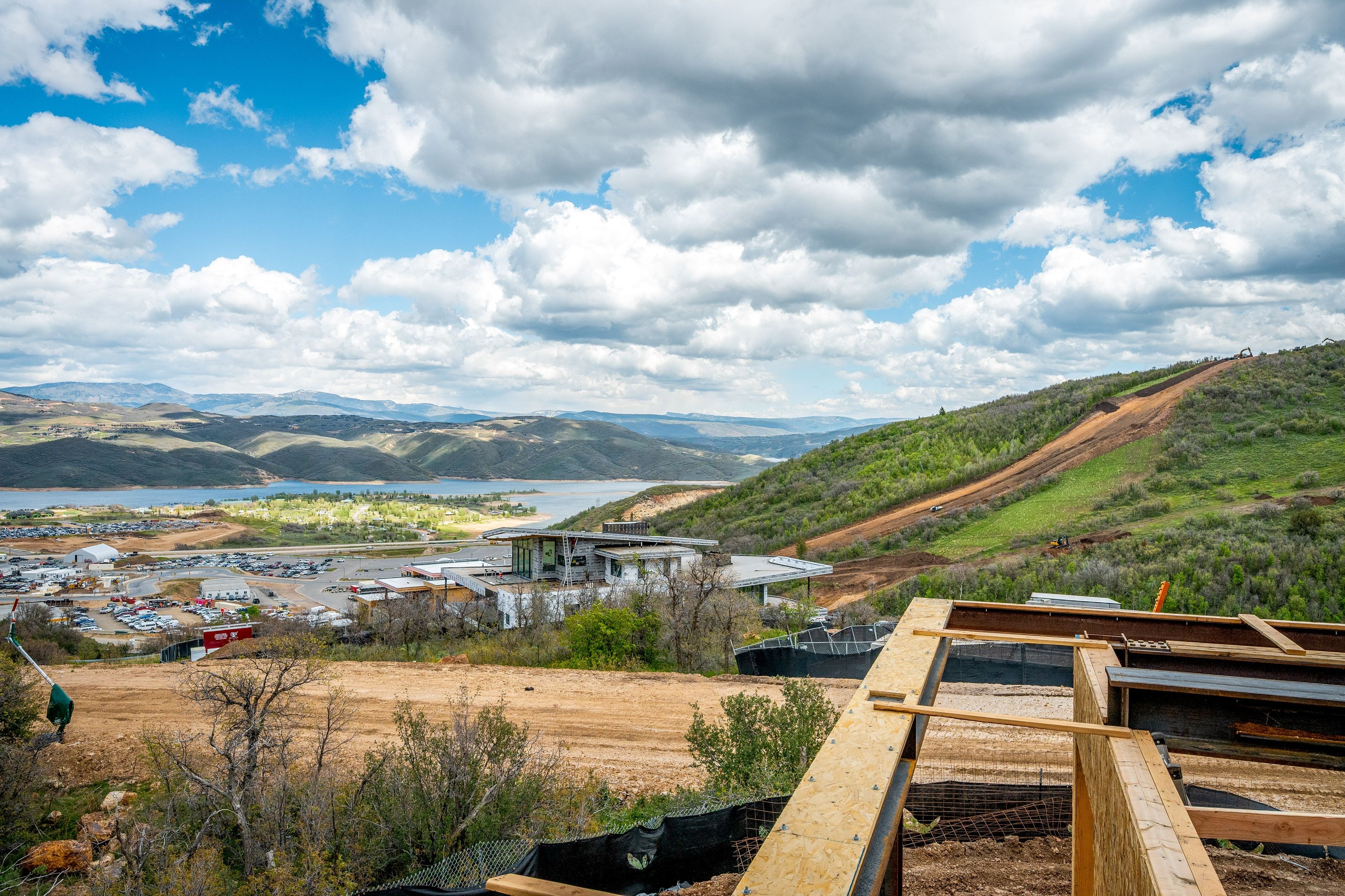 Property under construction featuring exposed wood framing, with an expansive landscape that includes distant mountains, a large body of water, and surrounding green hillsides