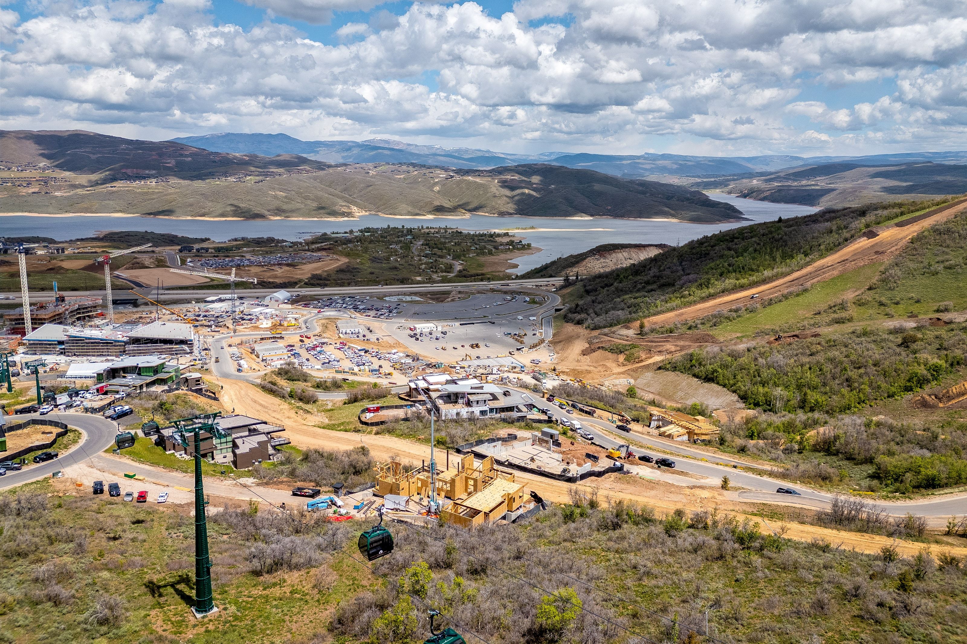 Aerial perspective showcasing a developing resort area with a prominent lake and mountainous landscape