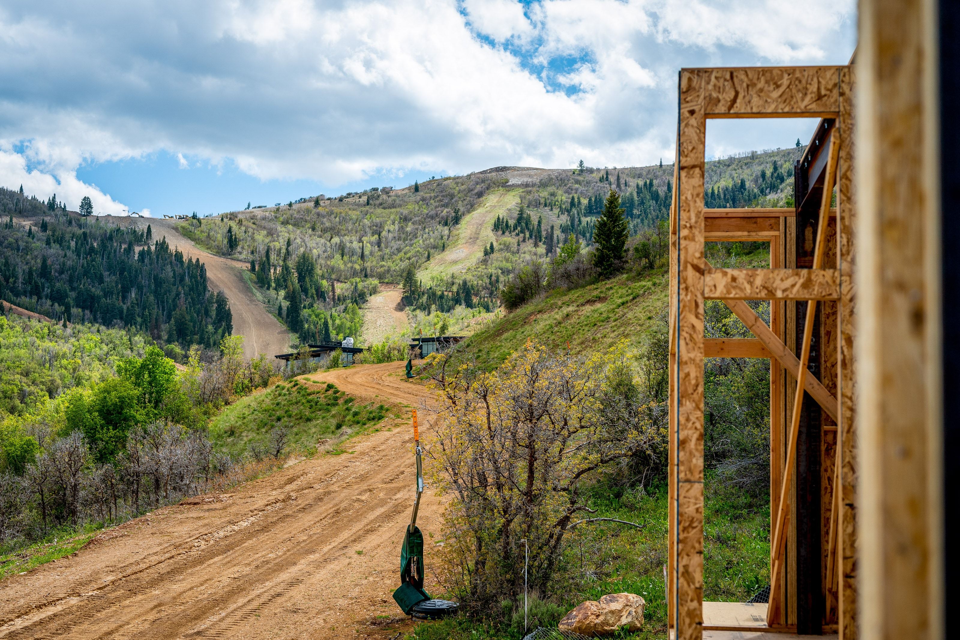 Framed structure with plywood sheathing, overlooking a mountainside landscape with ski runs and abundant trees