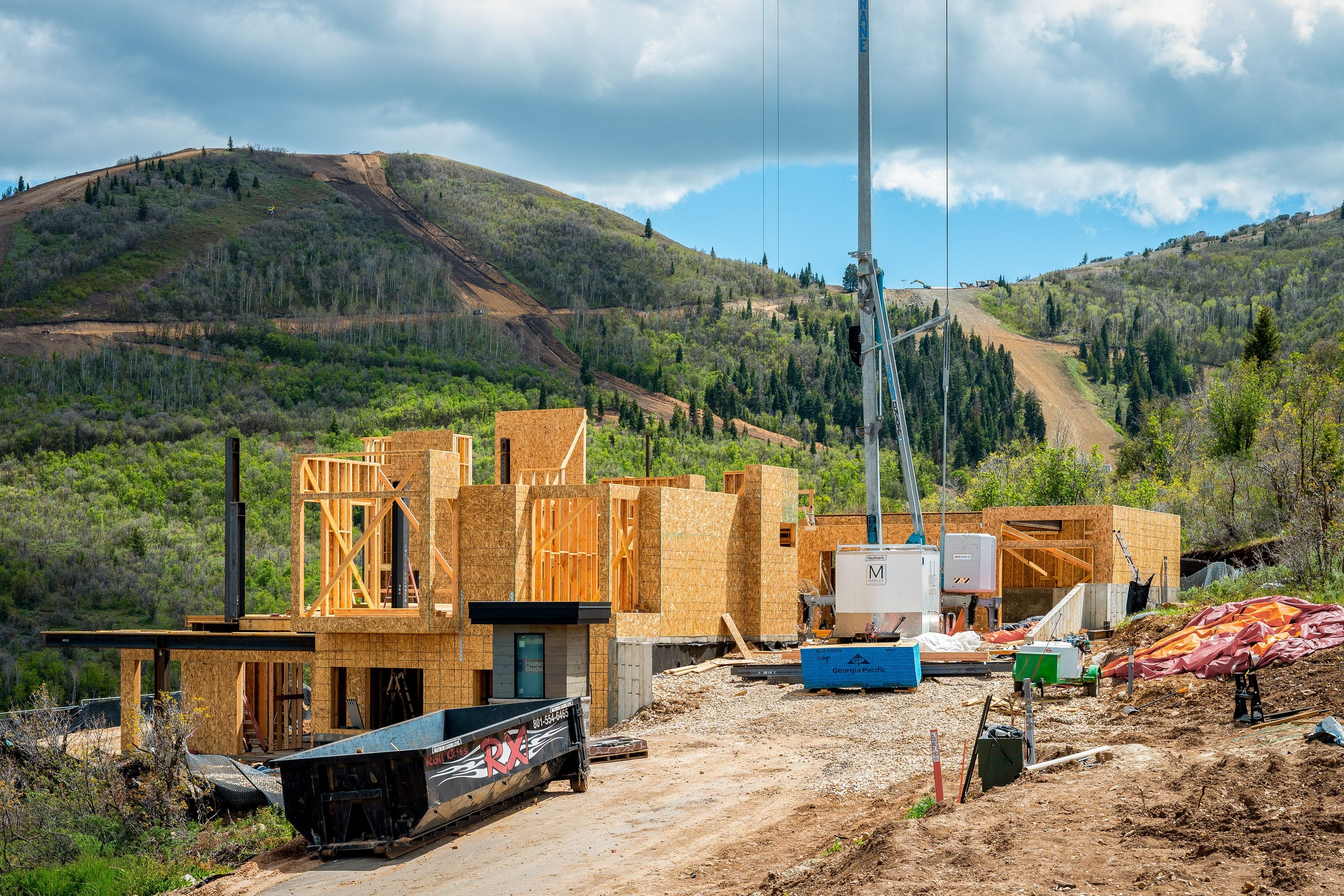 New construction property featuring multiple structural levels, a flat roofline, an integrated chimney, and a mountainous backdrop