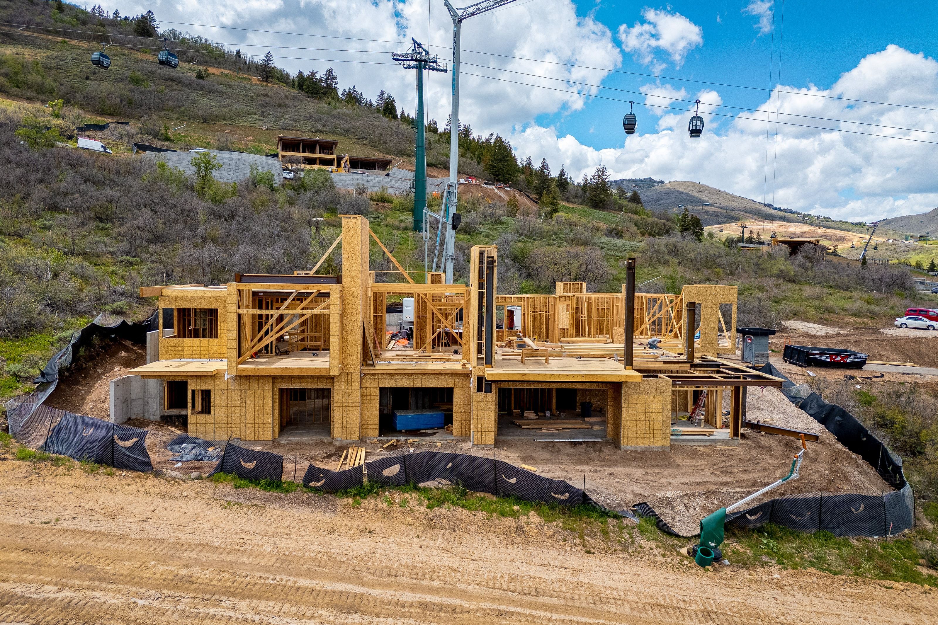 New construction property framed for a multi-level structure with multiple window openings and a prominent flat roof line