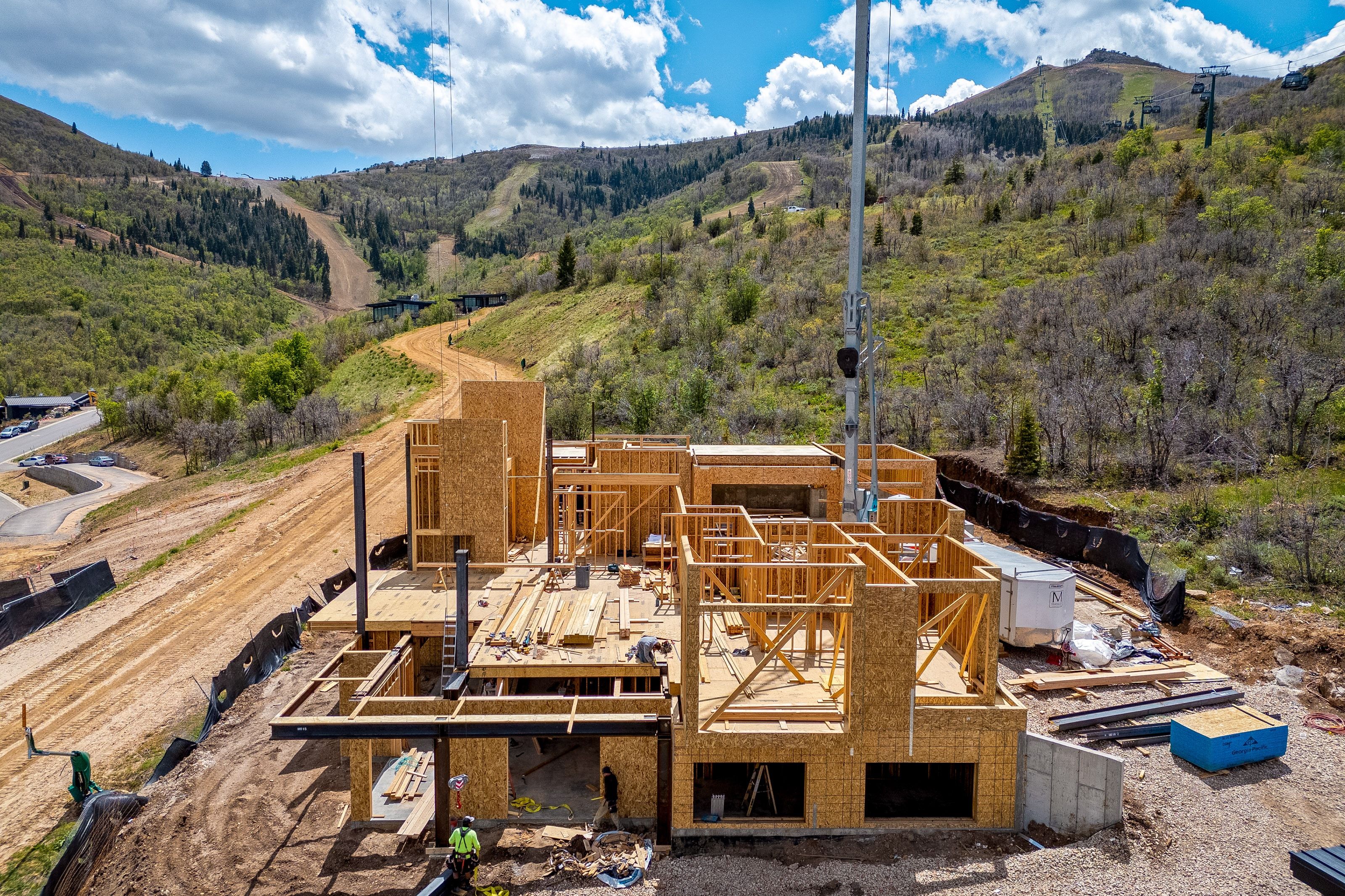 New construction framing on a sloped lot, featuring multiple levels and a partial concrete foundation