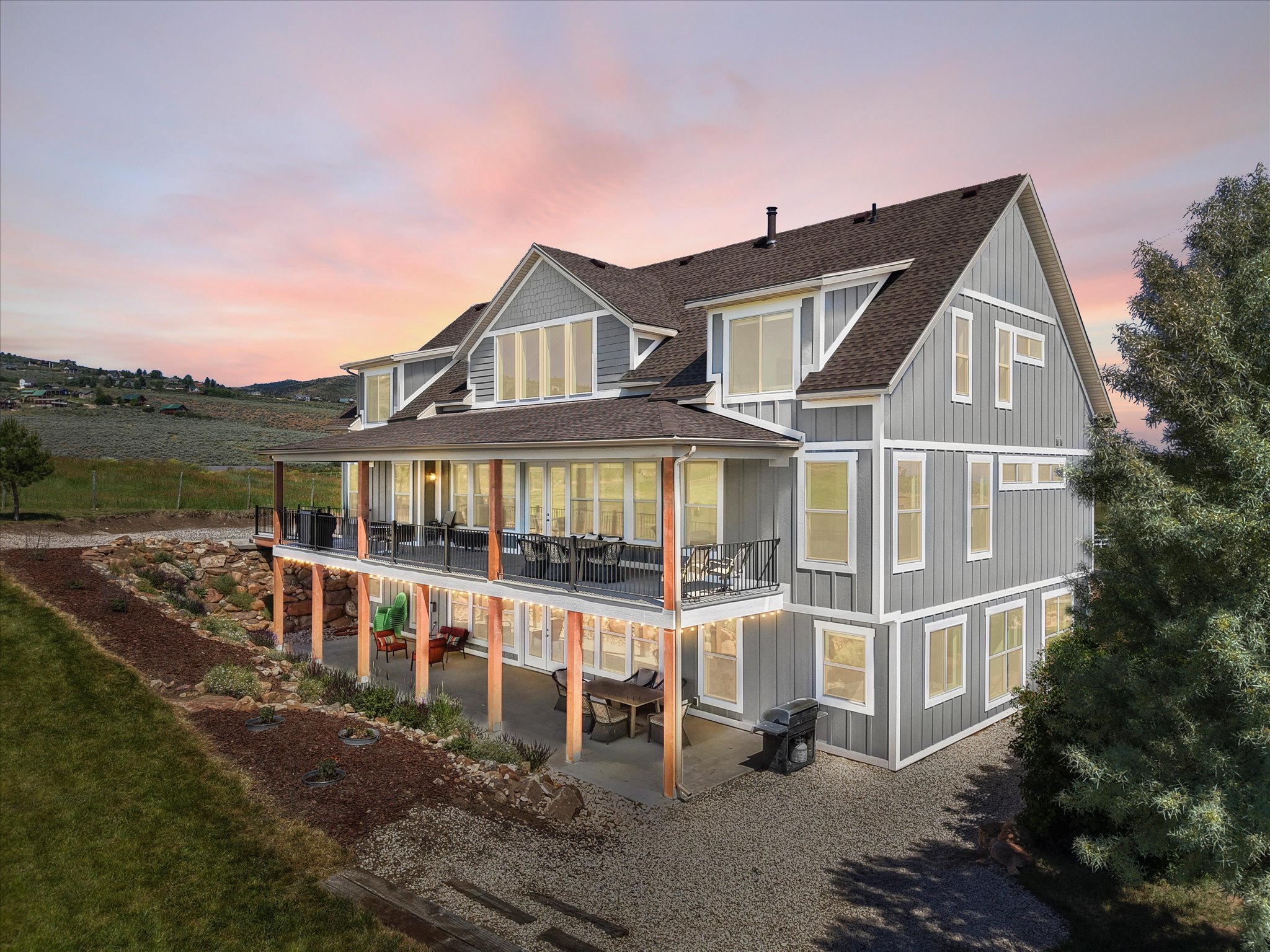 Multi-level residence featuring gray vertical siding, white trim, and a dark shingled roof