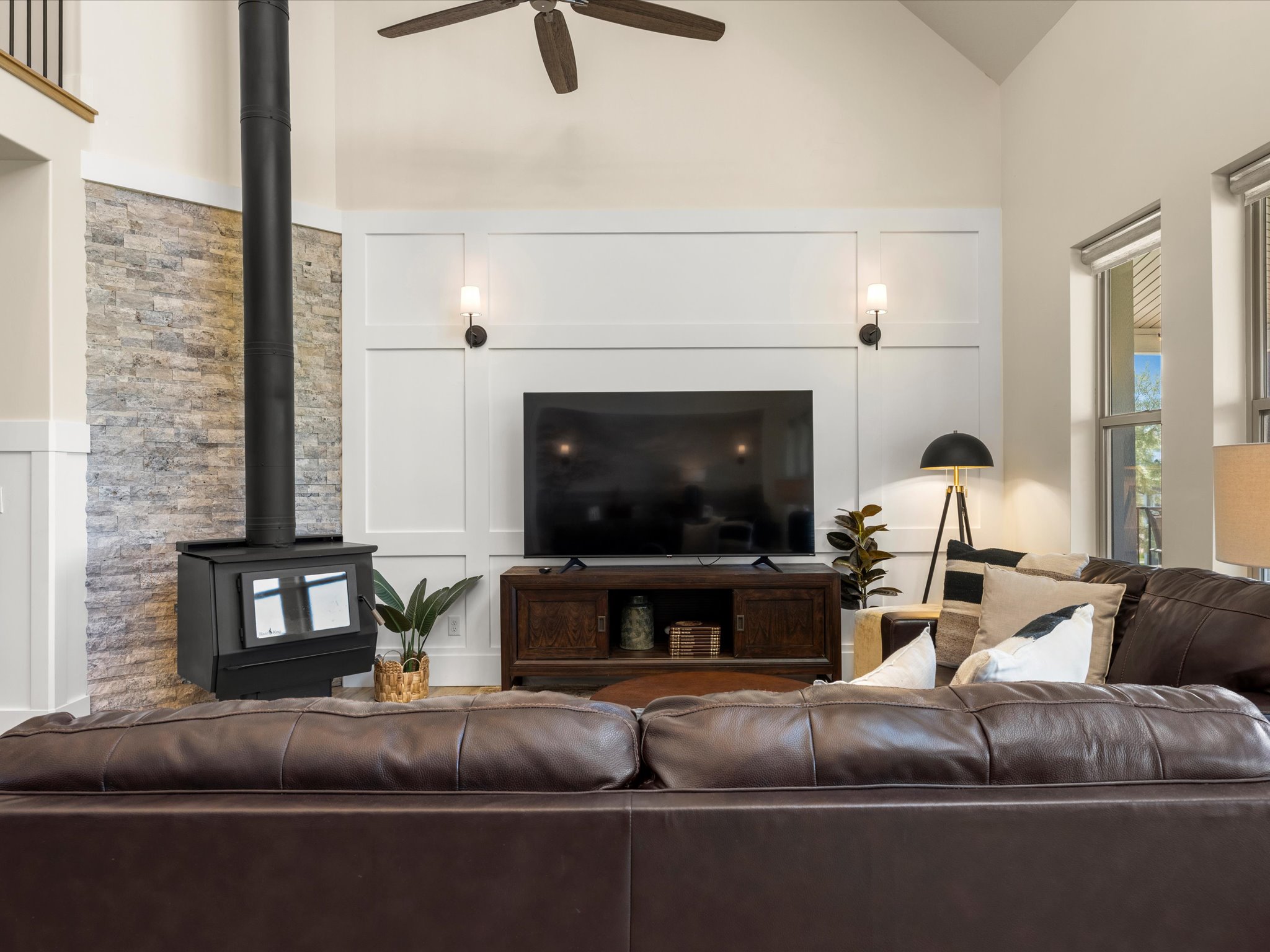Living area with a stone accent wall, wood-burning stove, and vaulted ceiling