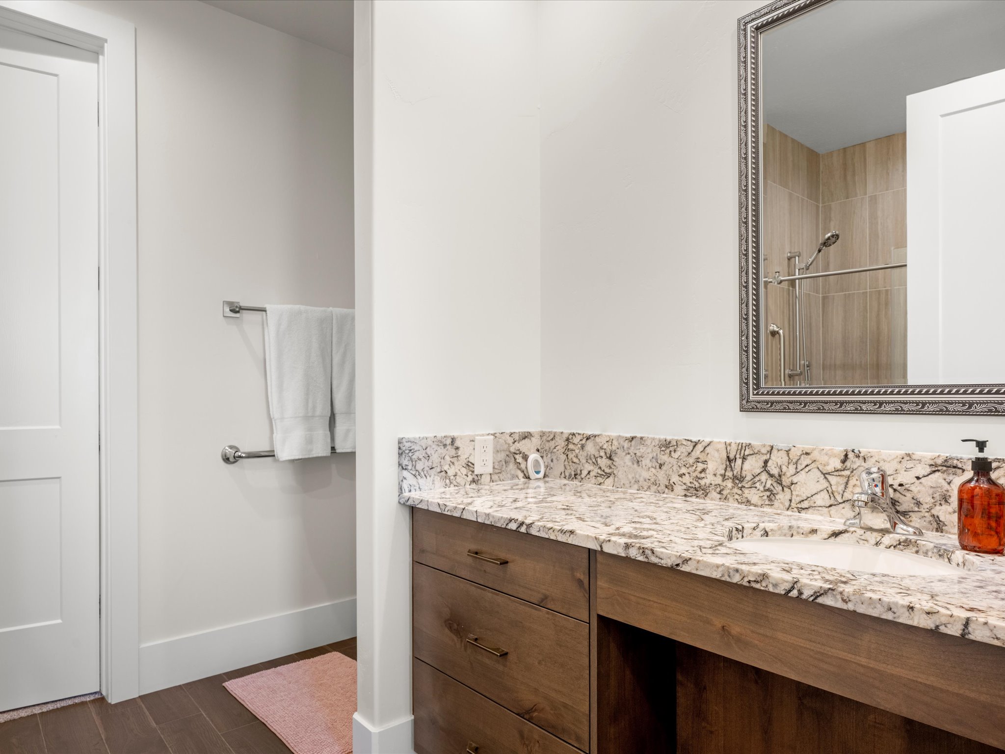 Bathroom vanity featuring a light-toned stone countertop, integrated sink, and dark wood cabinetry with bronze-finish hardware