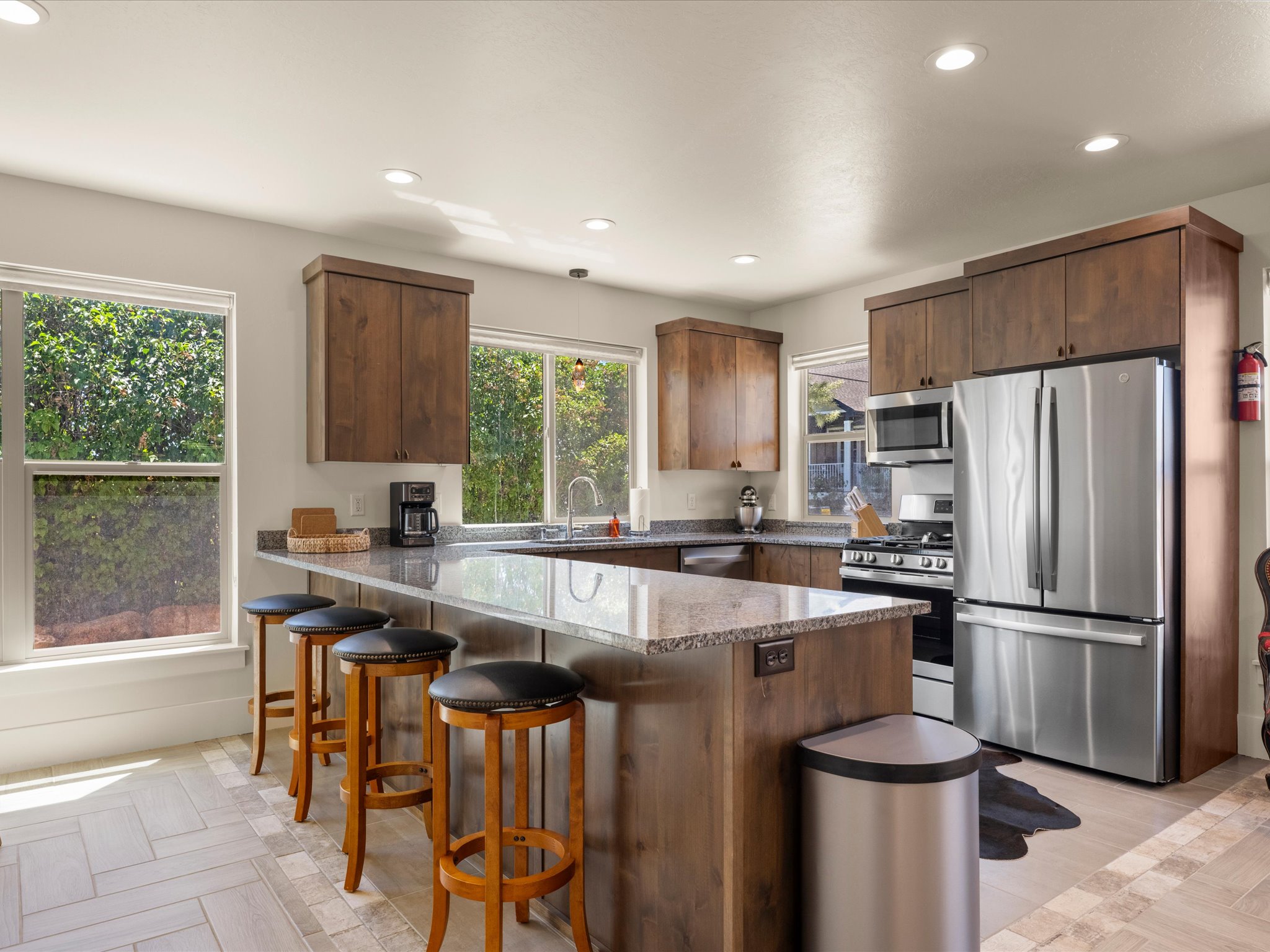 Kitchen featuring a large island with a stone countertop, wood-finish cabinetry, stainless steel appliances, and recessed lighting