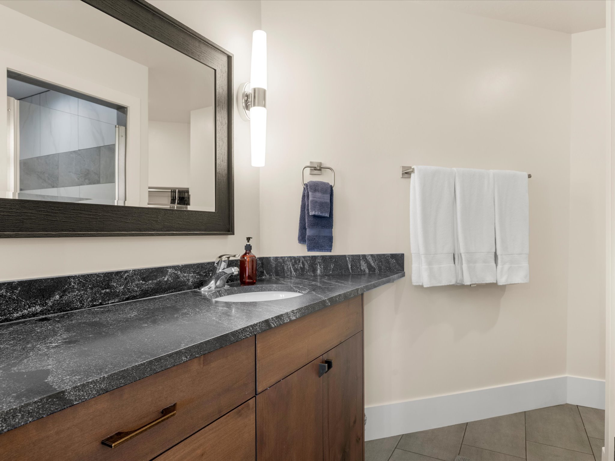 Bathroom vanity featuring a dark, patterned countertop, undermount sink, and wood-finish cabinetry