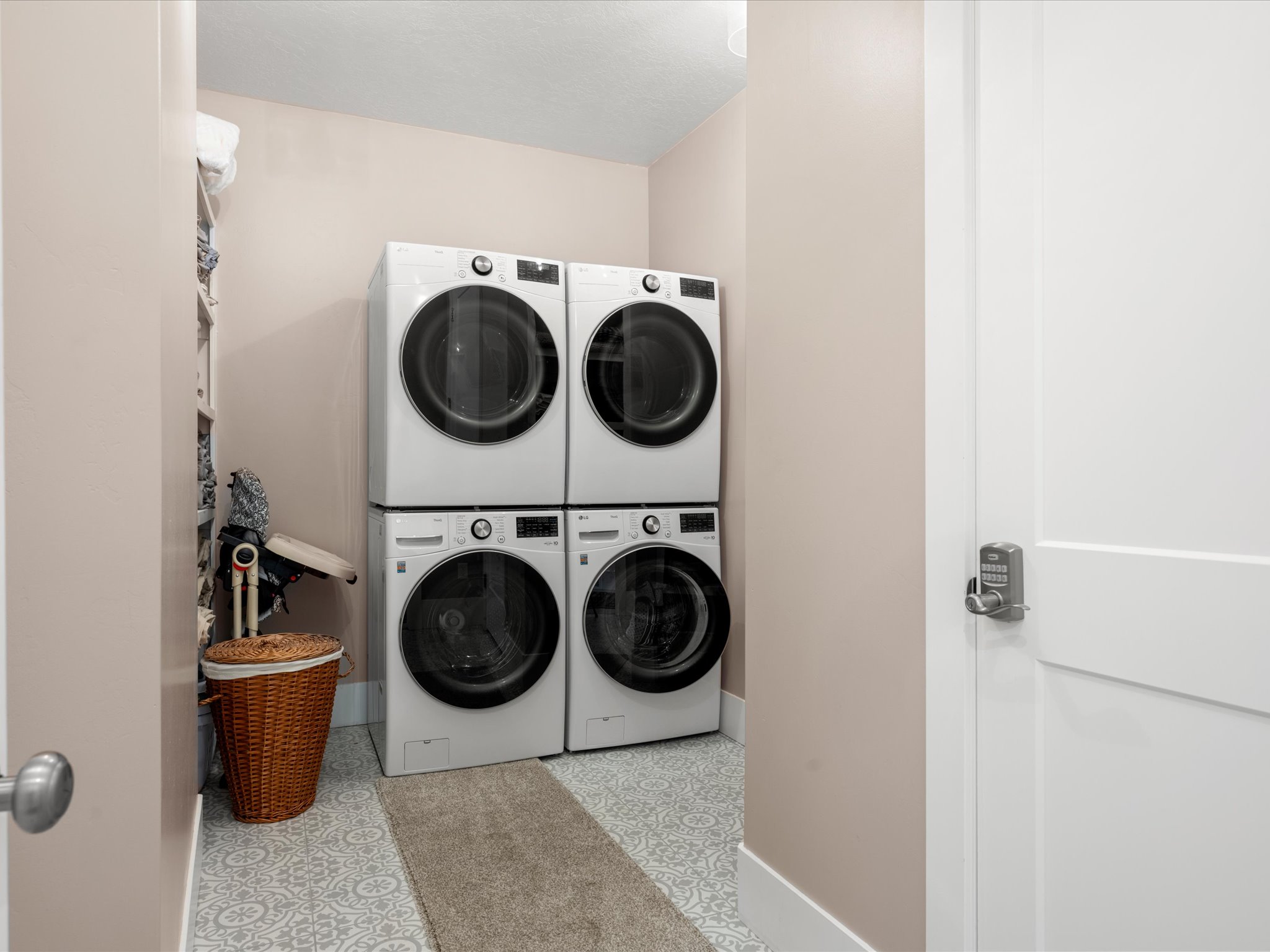 Dedicated laundry area featuring patterned tile flooring, a built-in shelving unit, and white baseboards